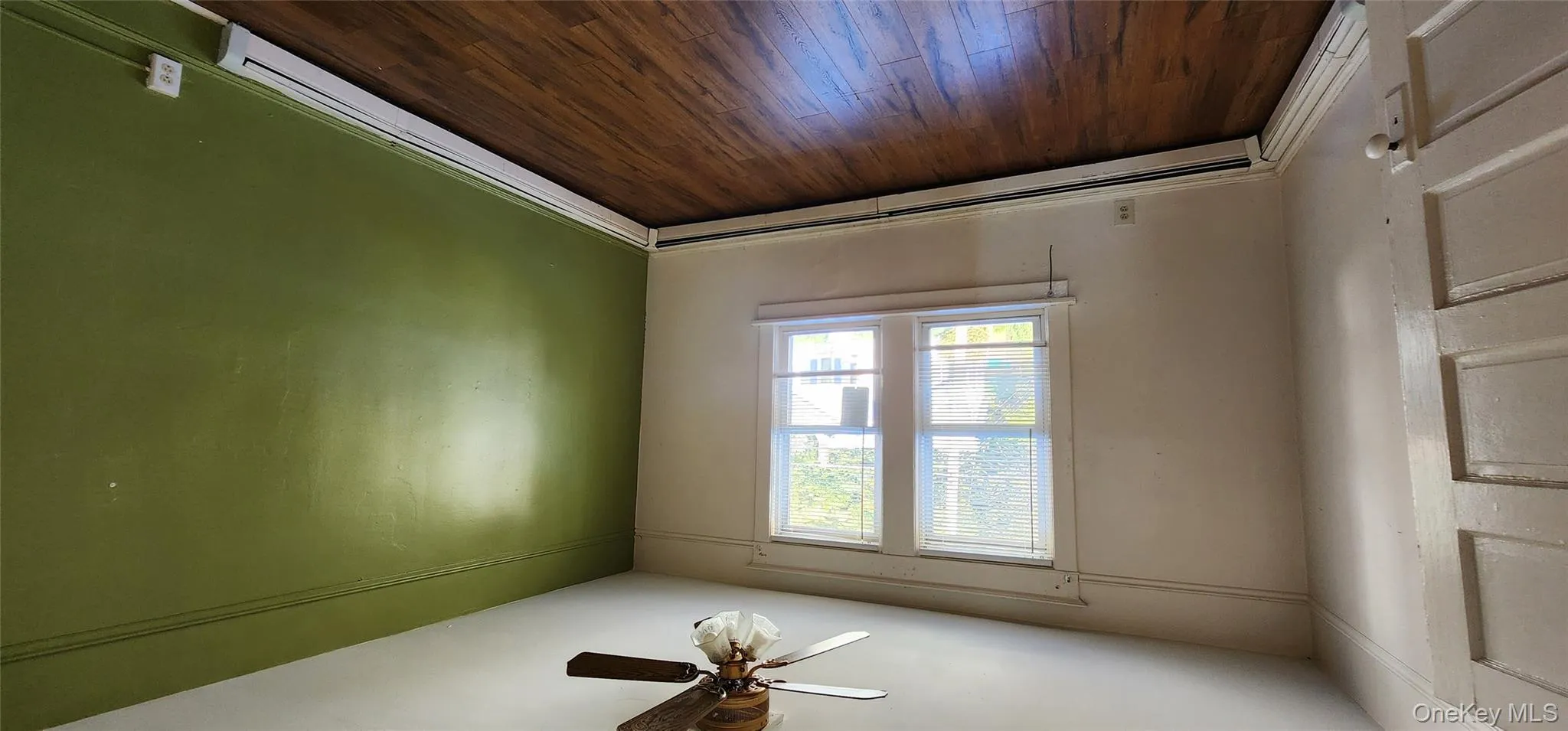 Unfurnished room featuring dark wood finished floors, a baseboard heating unit, and ceiling fan Unfurnished room featuring dark wood finished floors, a baseboard heating unit, and ceiling fan