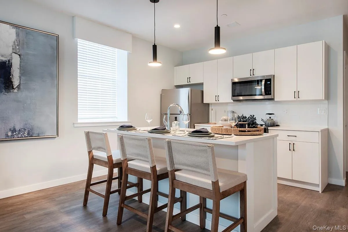 Kitchen featuring a breakfast bar, light countertops, white cabinets, tasteful backsplash, and recessed lighting Kitchen featuring a breakfast bar, light countertops, white cabinets, tasteful backsplash, and recessed lighting