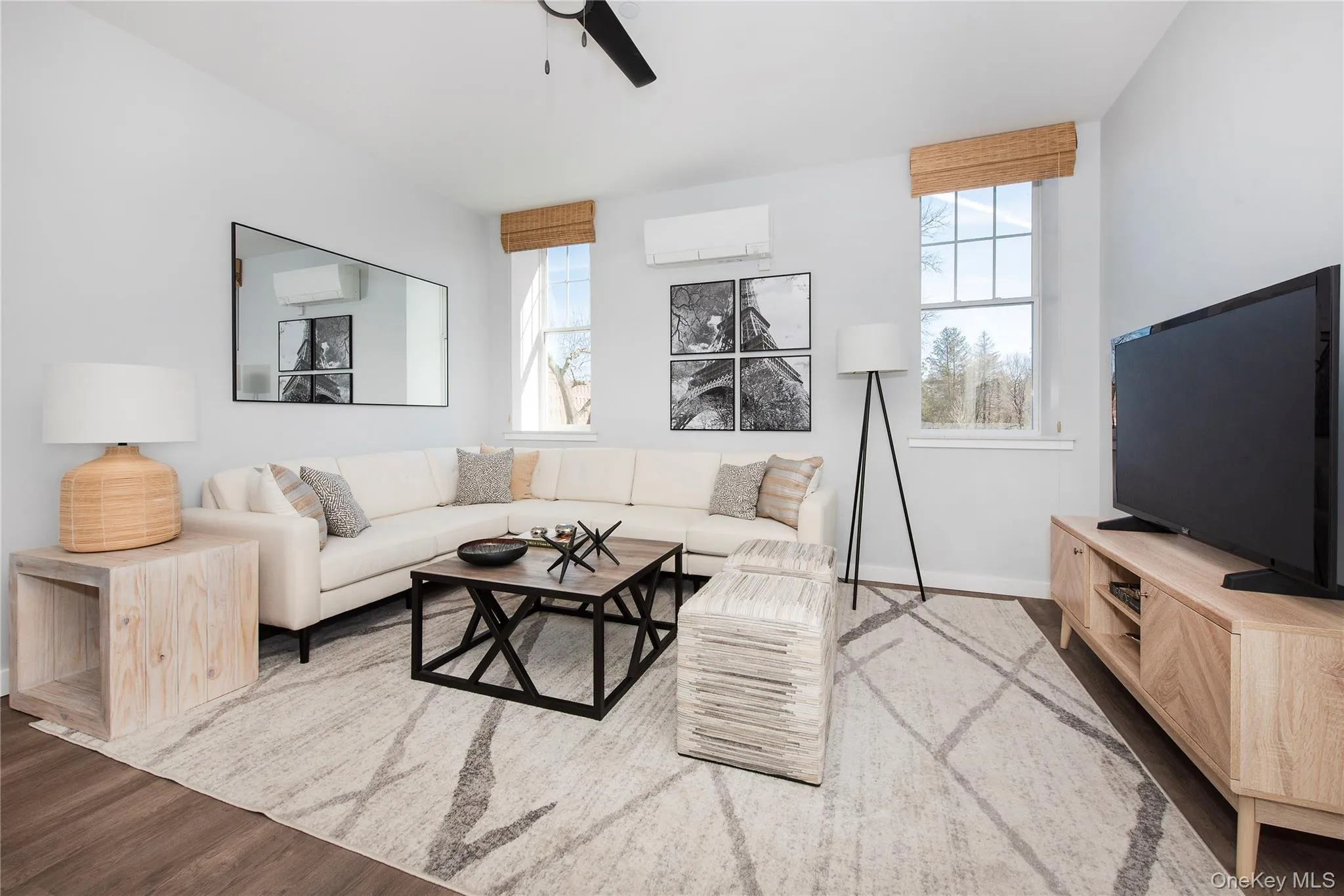 Living room with healthy amount of natural light, wood finished floors, an AC wall unit, and a ceiling fan Living room with healthy amount of natural light, wood finished floors, an AC wall unit, and a ceiling fan
