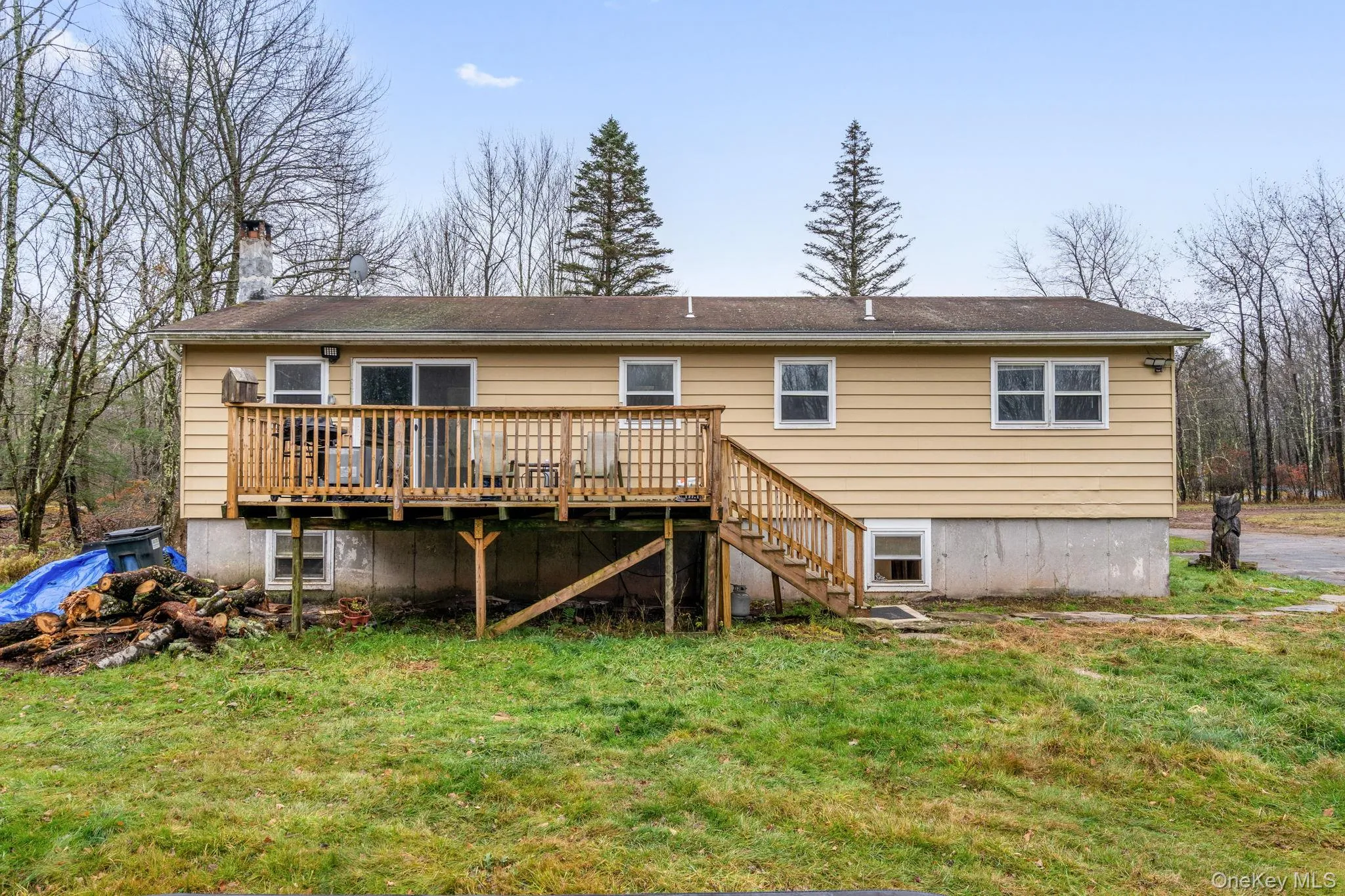Rear view of house featuring stairs, a deck, a chimney, and a yard Rear view of house featuring stairs, a deck, a chimney, and a yard