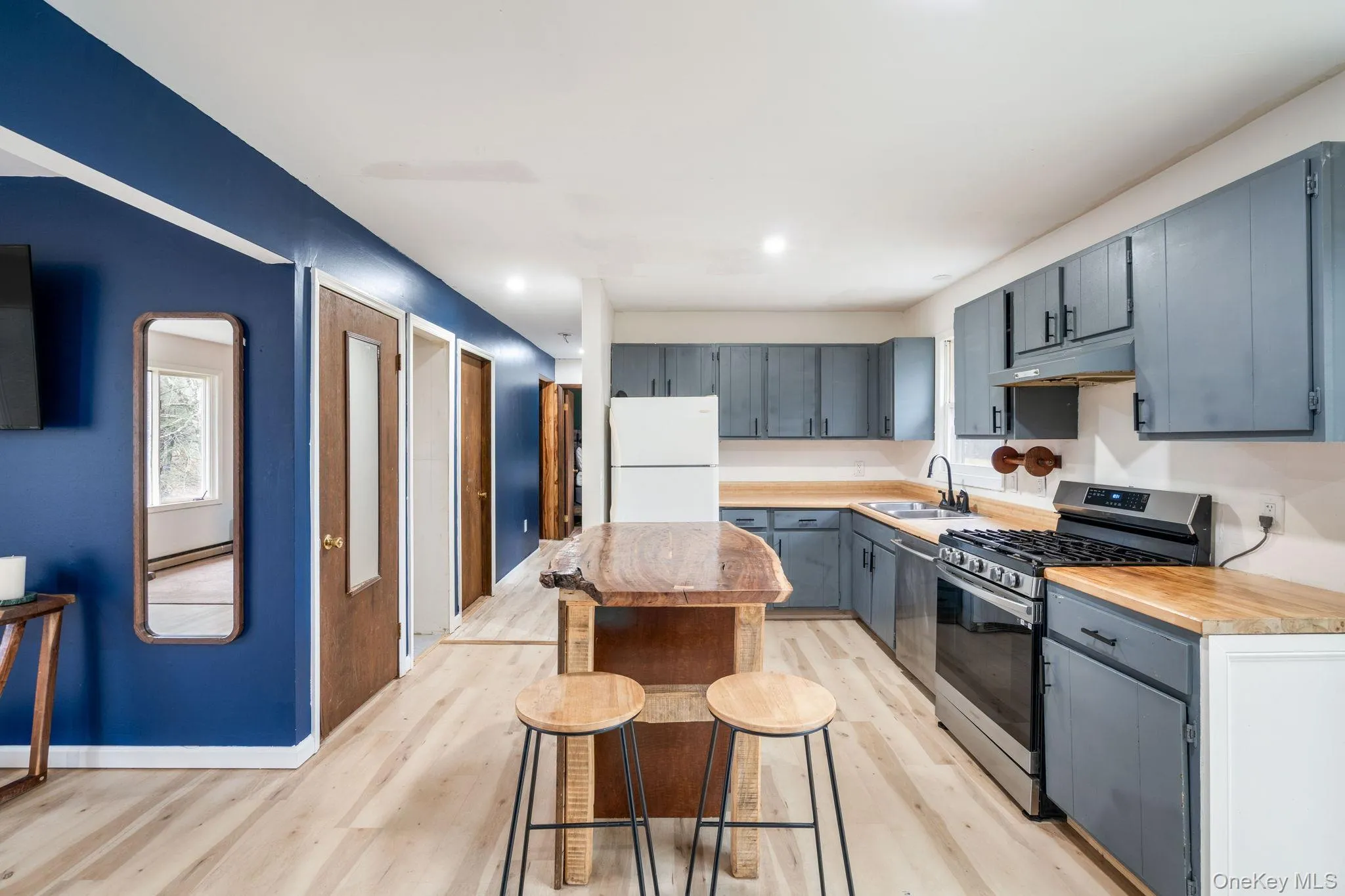 Kitchen featuring stainless steel appliances, wooden counters, a center island, light wood-type flooring, and recessed lighting Kitchen featuring stainless steel appliances, wooden counters, a center island, light wood-type flooring, and recessed lighting
