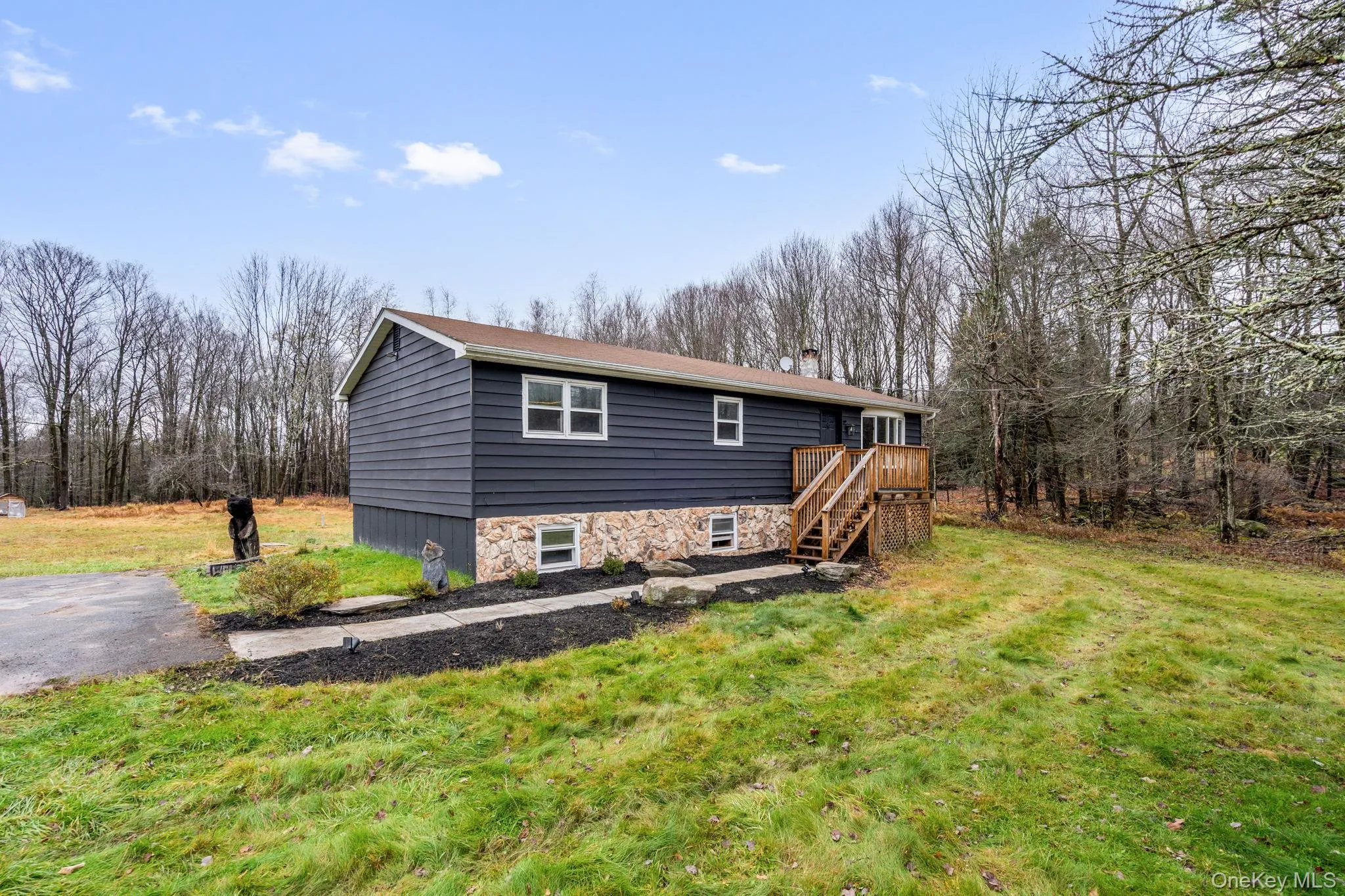 Rear view of house with a lawn, stairs, stone siding, and a wooden deck Rear view of house with a lawn, stairs, stone siding, and a wooden deck