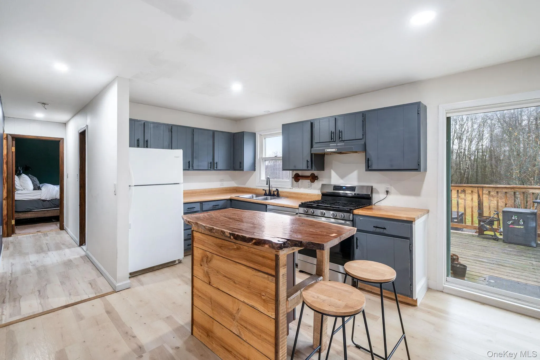 Kitchen featuring gas stove, freestanding refrigerator, a kitchen island, a breakfast bar area, and light wood-type flooring Kitchen featuring gas stove, freestanding refrigerator, a kitchen island, a breakfast bar area, and light wood-type flooring