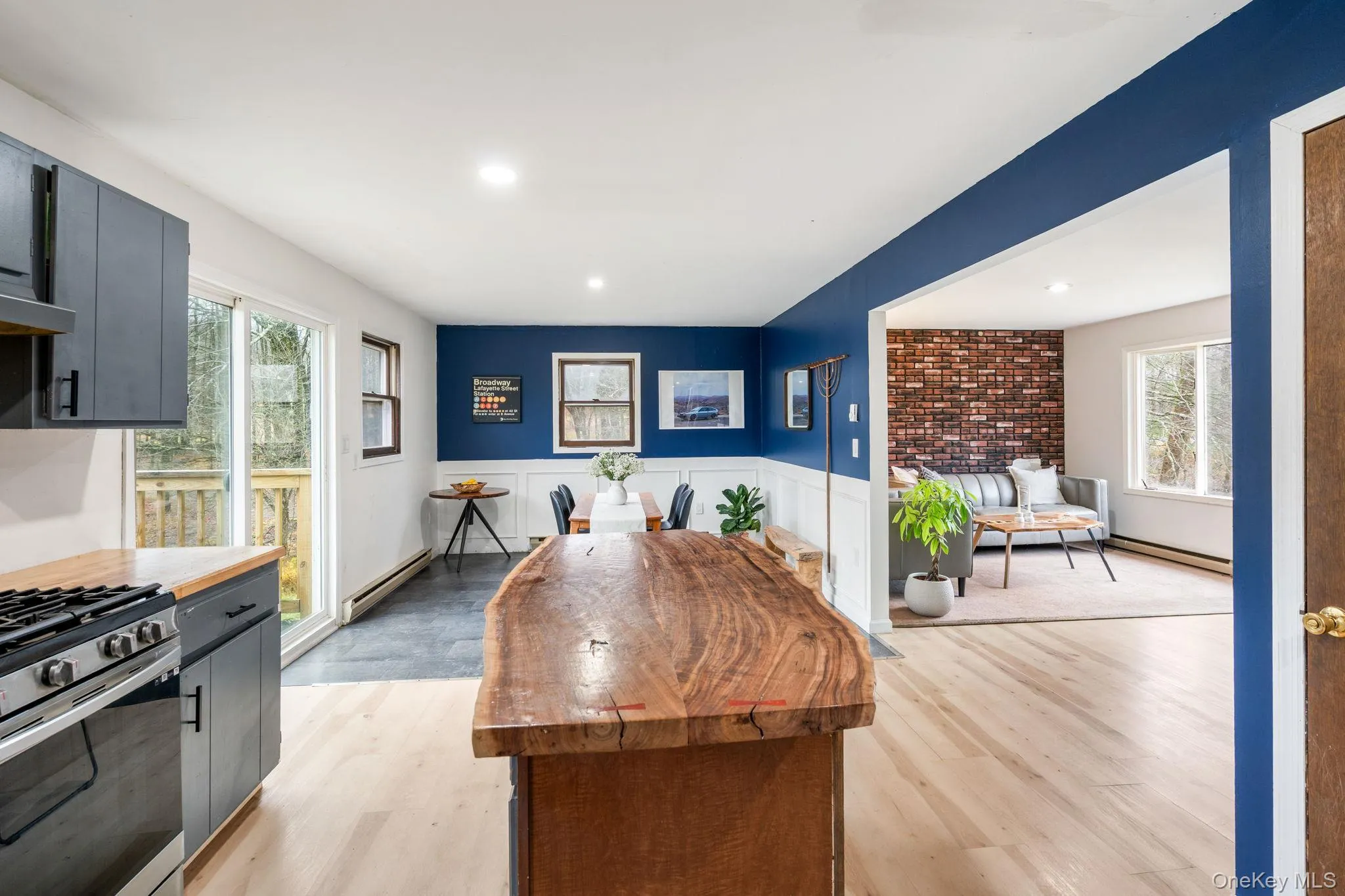 Kitchen featuring wooden counters, a wainscoted wall, light wood finished floors, a baseboard heating unit, and stainless steel gas range oven Kitchen featuring wooden counters, a wainscoted wall, light wood finished floors, a baseboard heating unit, and stainless steel gas range oven