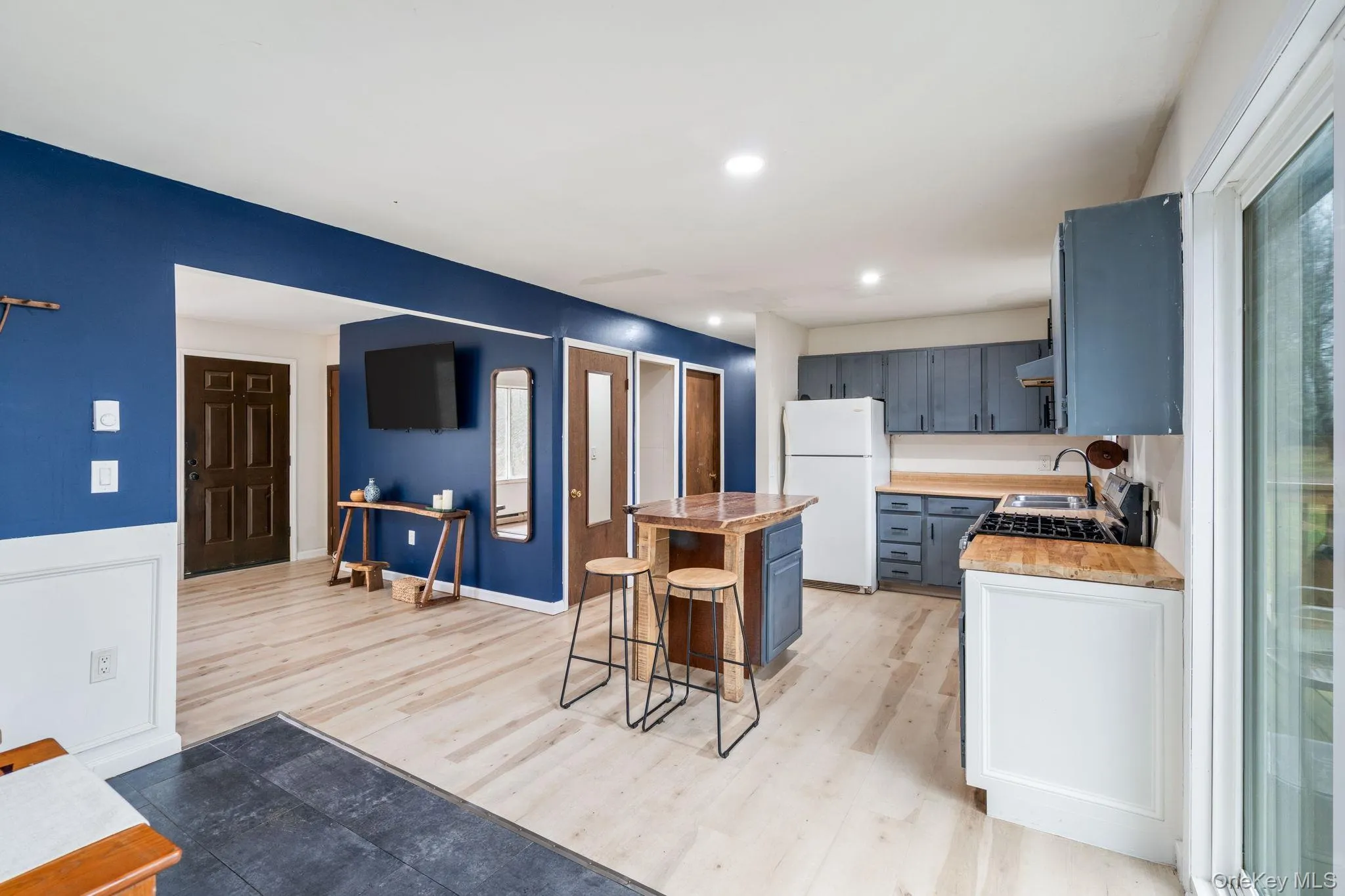Kitchen with a kitchen island, a breakfast bar area, light countertops, freestanding refrigerator, and light wood-type flooring Kitchen with a kitchen island, a breakfast bar area, light countertops, freestanding refrigerator, and light wood-type flooring
