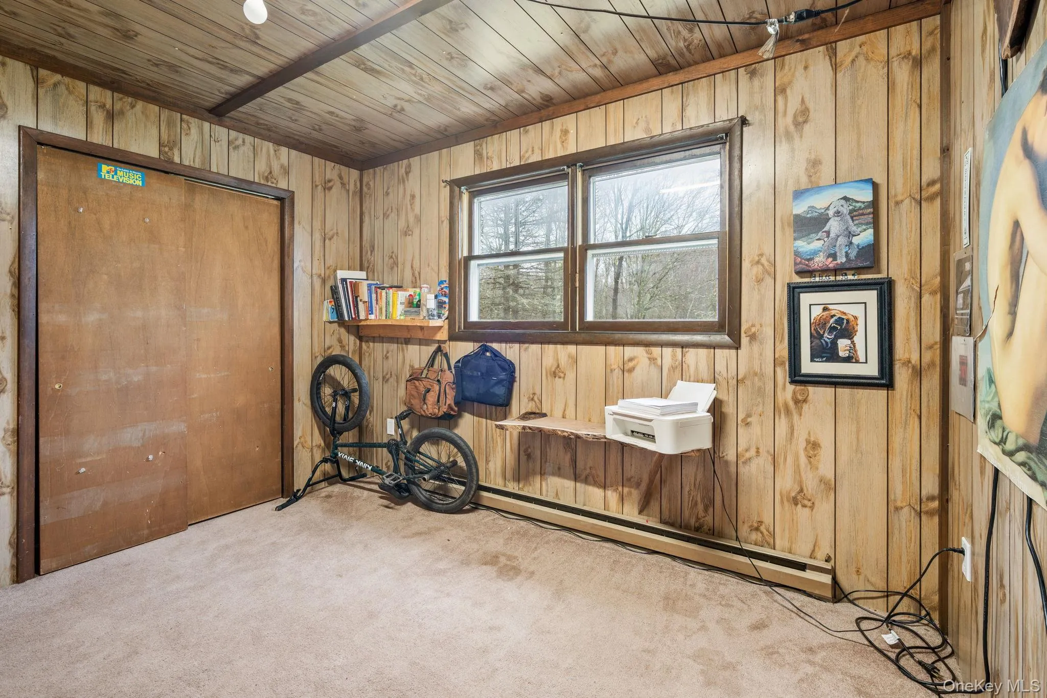 Carpeted bedroom featuring wooden walls, a closet, and wood ceiling Carpeted bedroom featuring wooden walls, a closet, and wood ceiling