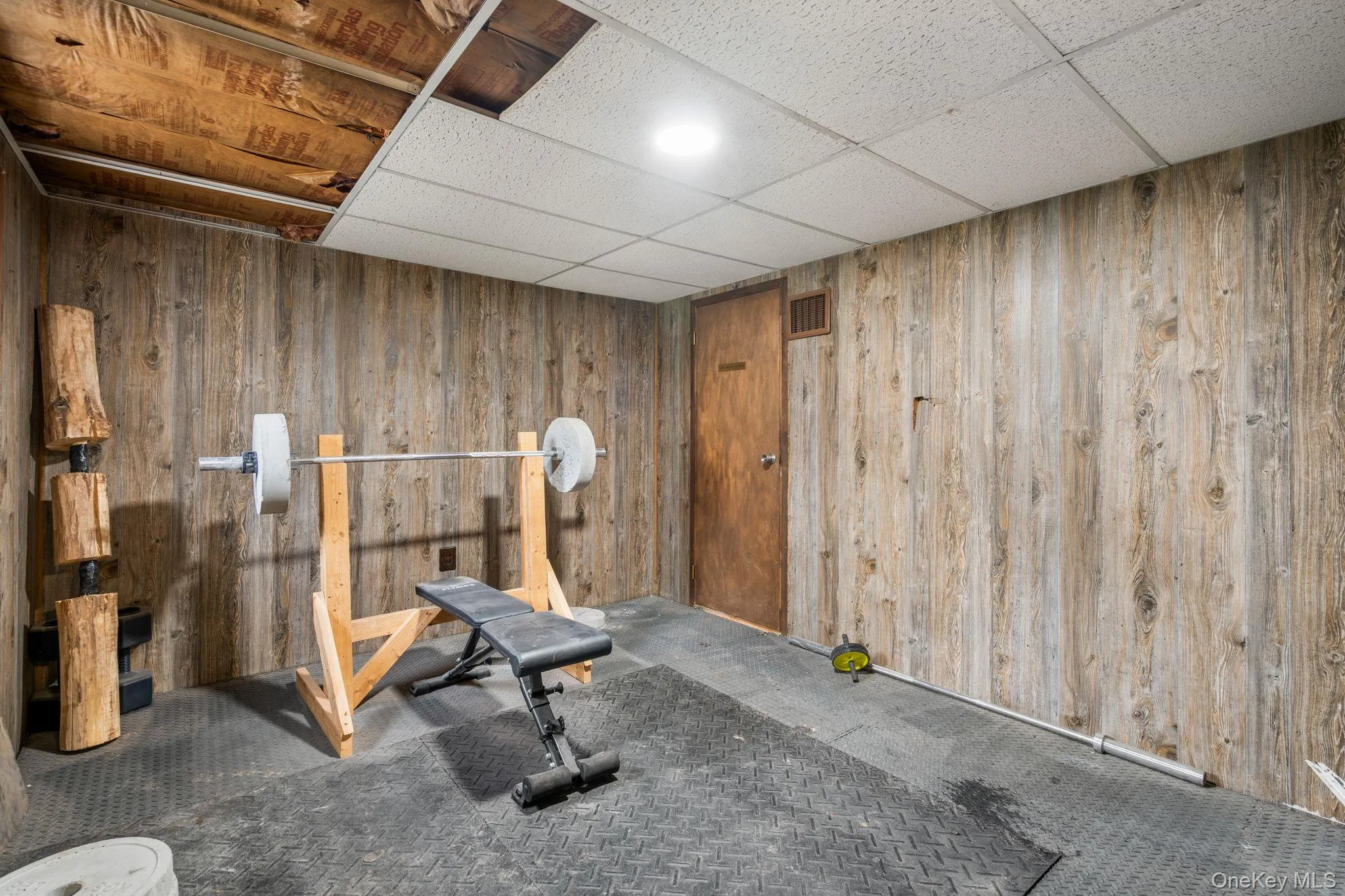 Workout room with wooden walls, a paneled ceiling, and carpet flooring Workout room with wooden walls, a paneled ceiling, and carpet flooring