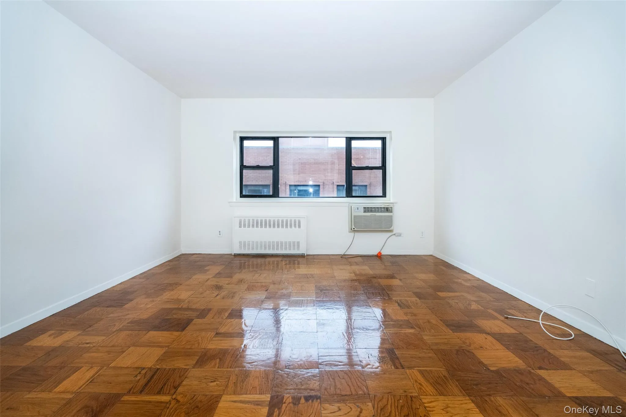 Living room featuring hardwood floors, radiator, in wall A/C Unit Living room featuring hardwood floors, radiator, in wall A/C Unit