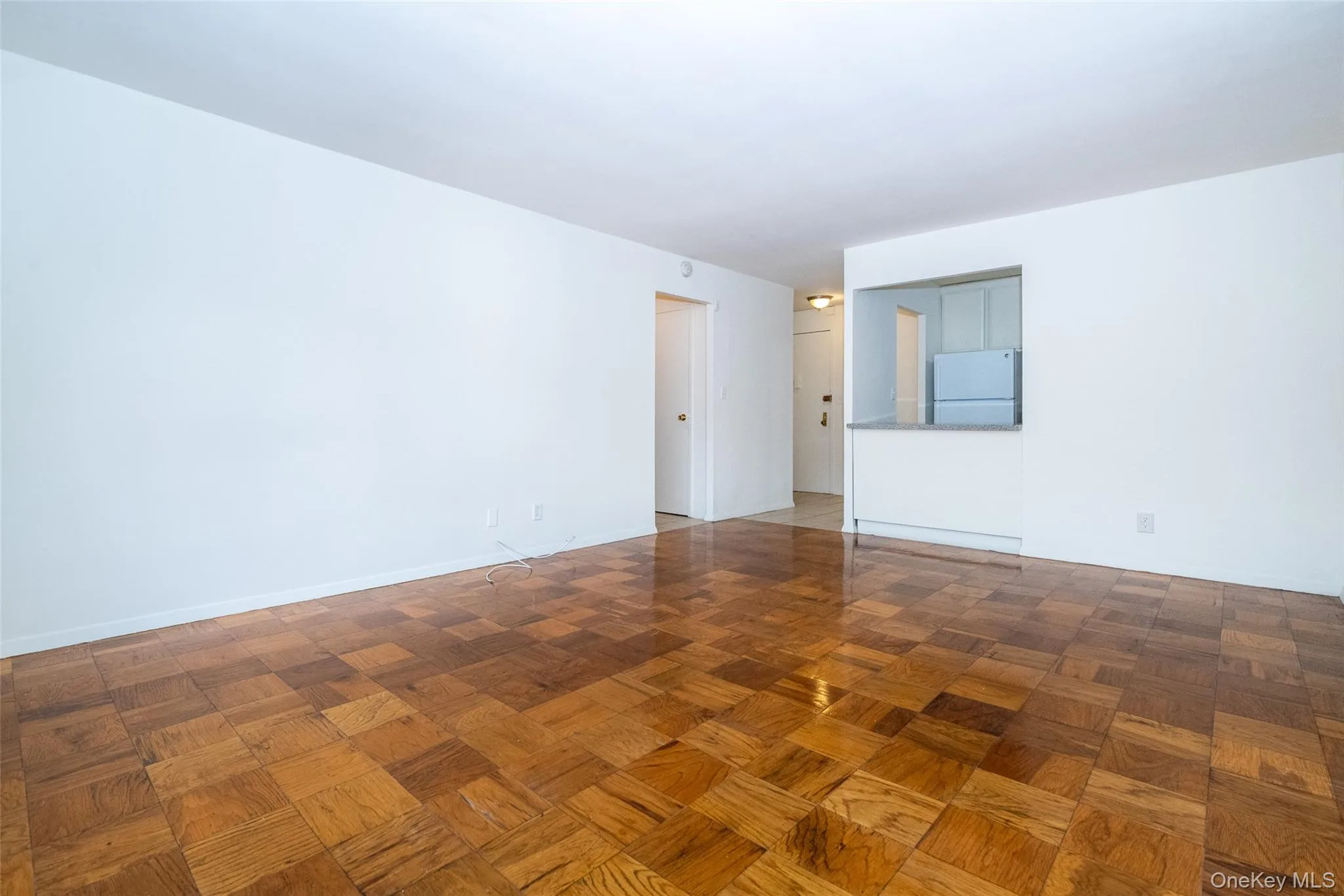 Living room facing toward kitchen - featuring hardwood floors, radiator, in wall A/C Unit Living room facing toward kitchen - featuring hardwood floors, radiator, in wall A/C Unit