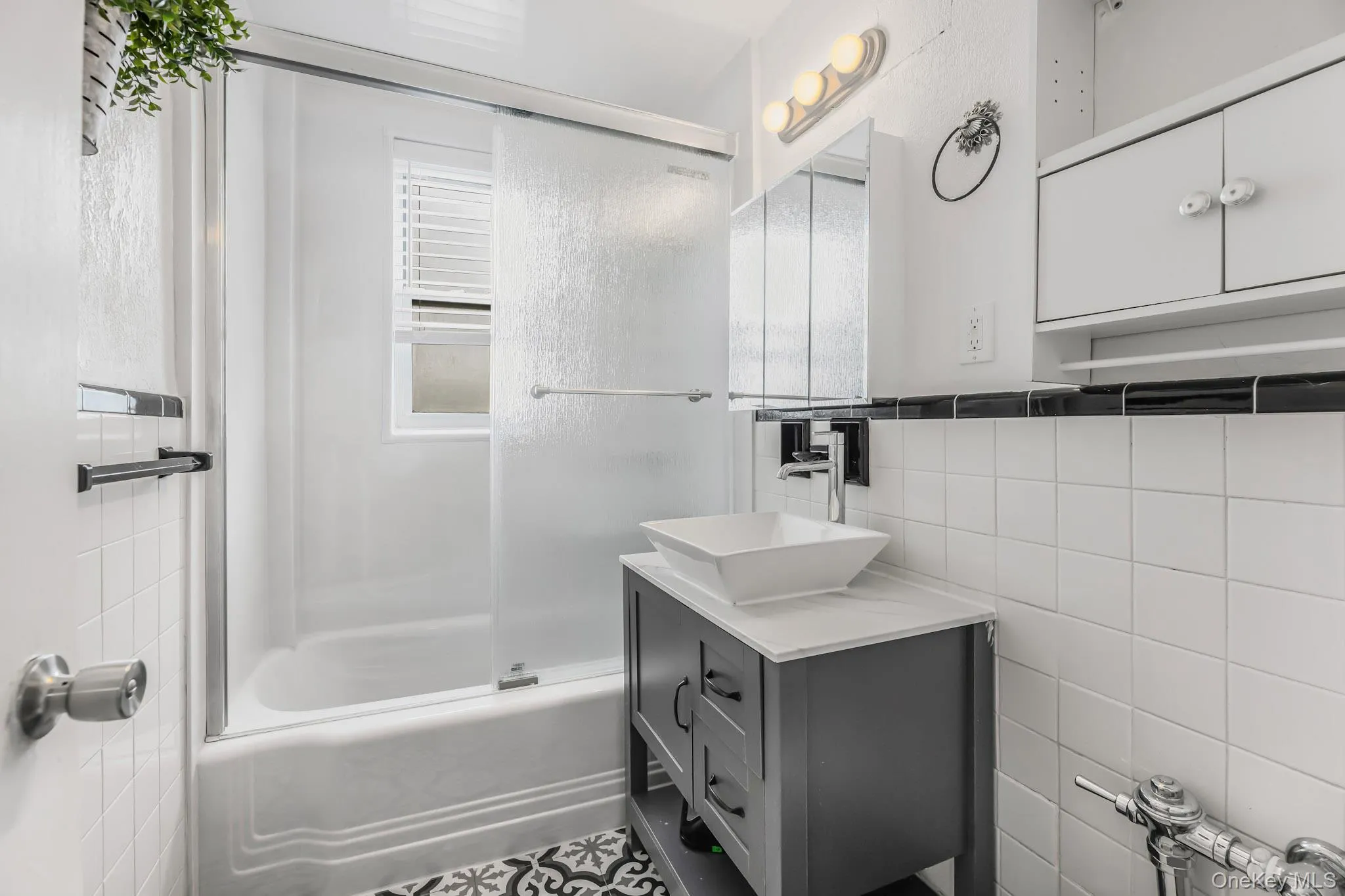 Full bath with tile walls, combined bath / shower with glass door, and vanity Full bath with tile walls, combined bath / shower with glass door, and vanity