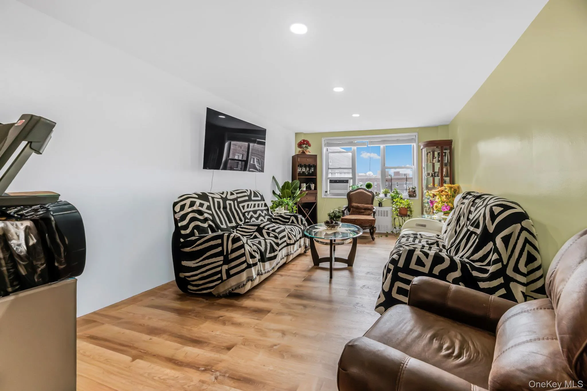Living area with wood finished floors, recessed lighting, and radiator heating unit Living area with wood finished floors, recessed lighting, and radiator heating unit