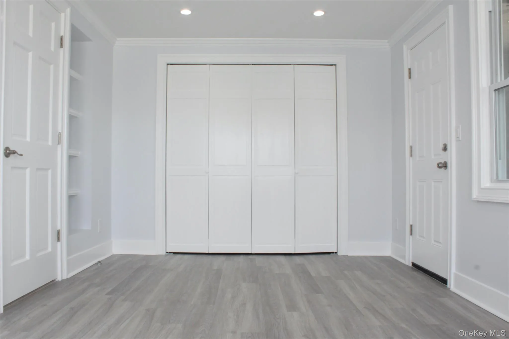 Unfurnished bedroom featuring ornamental molding, wood finished floors, and a closet Unfurnished bedroom featuring ornamental molding, wood finished floors, and a closet