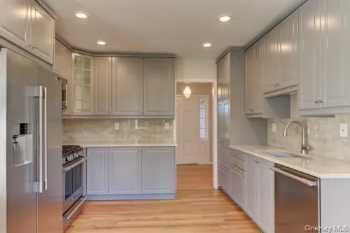 Kitchen with appliances with stainless steel finishes, backsplash, gray cabinetry, light wood-style flooring, and recessed lighting Kitchen with appliances with stainless steel finishes, backsplash, gray cabinetry, light wood-style flooring, and recessed lighting