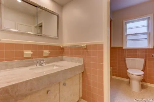 Bathroom featuring wainscoting, tile walls, vanity, and light tile patterned flooring Bathroom featuring wainscoting, tile walls, vanity, and light tile patterned flooring