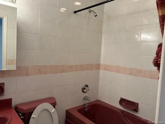 Full bathroom featuring shower / tub combination, tile walls, and vanity Full bathroom featuring shower / tub combination, tile walls, and vanity
