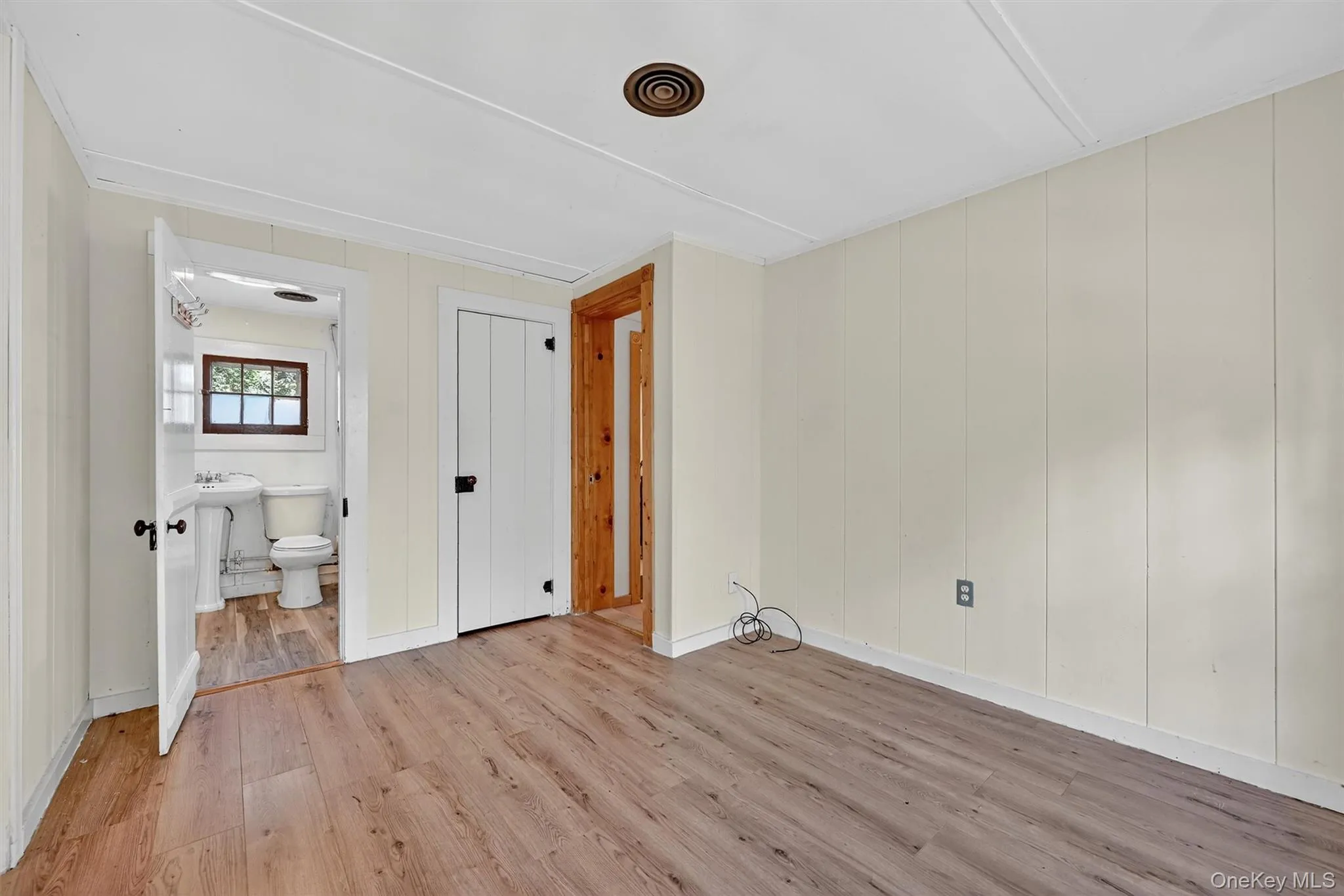 Unfurnished bedroom with wood finished floors and connected bathroom Unfurnished bedroom with wood finished floors and connected bathroom