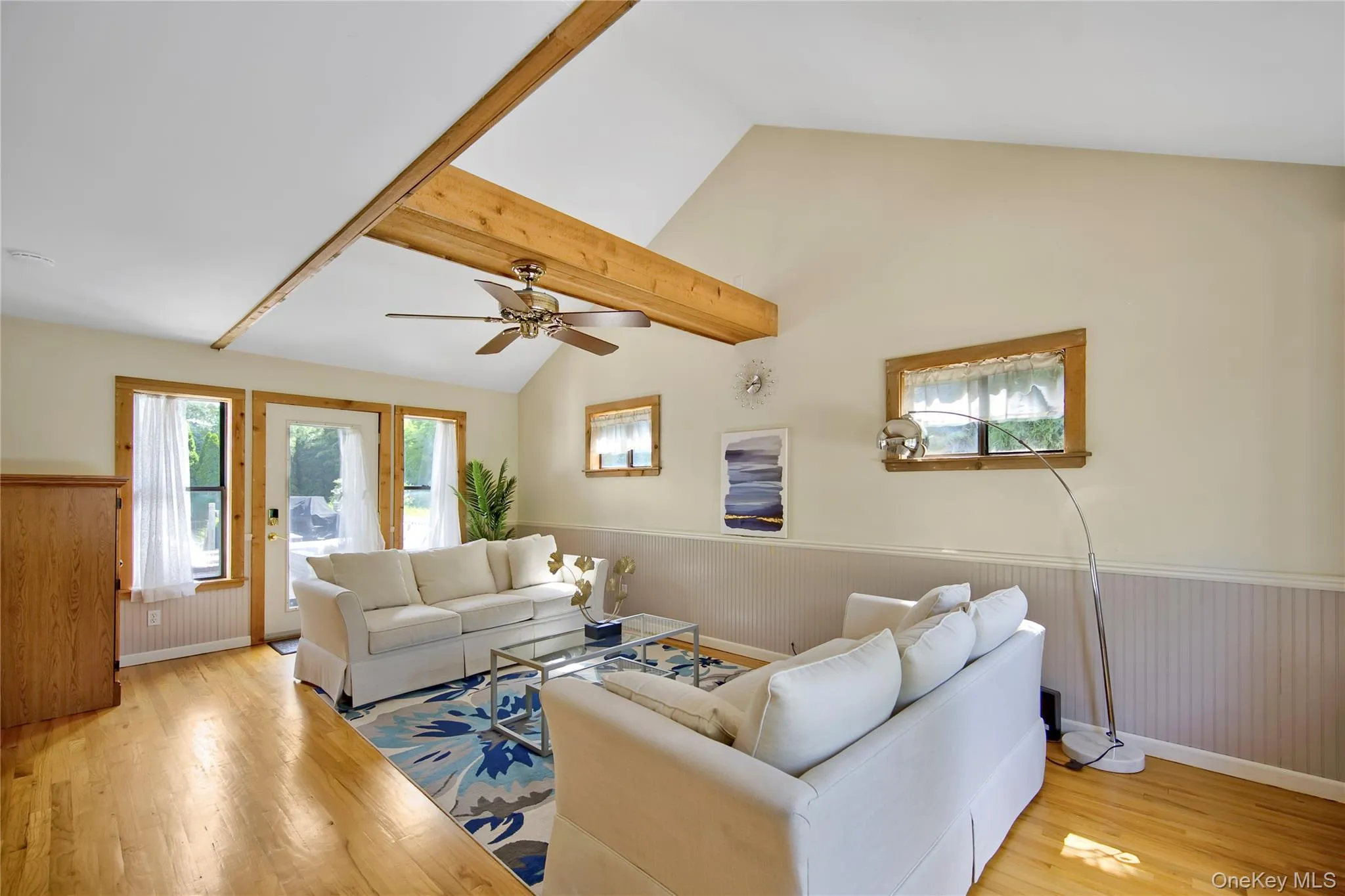 Living room with wainscoting, light wood-style flooring, healthy amount of natural light, ceiling fan, and wood walls Living room with wainscoting, light wood-style flooring, healthy amount of natural light, ceiling fan, and wood walls