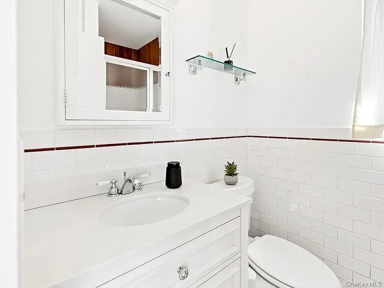 Ensuite with tile walls, vanity, a shower with door, and a wainscoted wall Ensuite with tile walls, vanity, a shower with door, and a wainscoted wall
