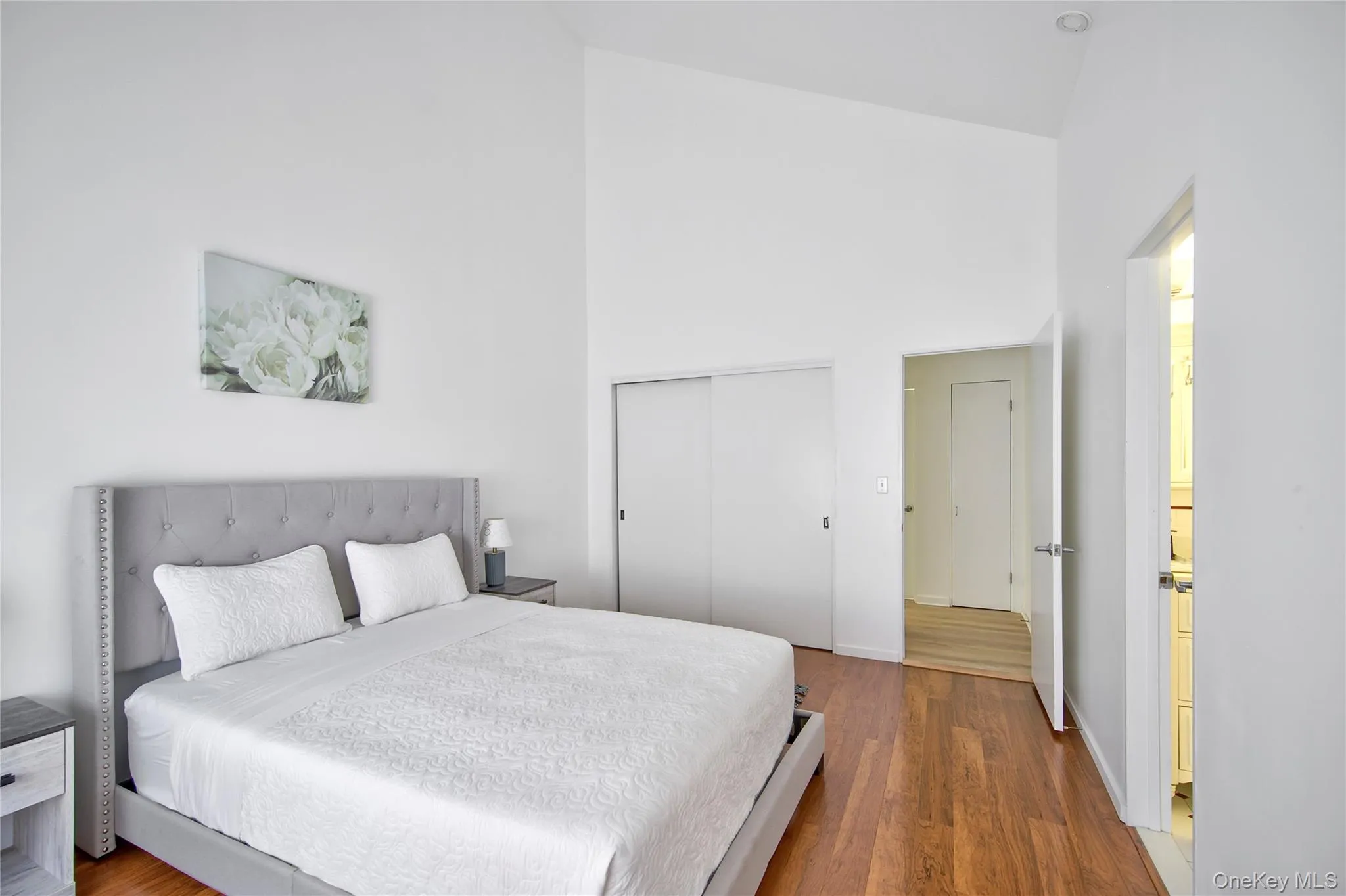 Bedroom with a high ceiling, dark wood-style floors, and a closet Bedroom with a high ceiling, dark wood-style floors, and a closet