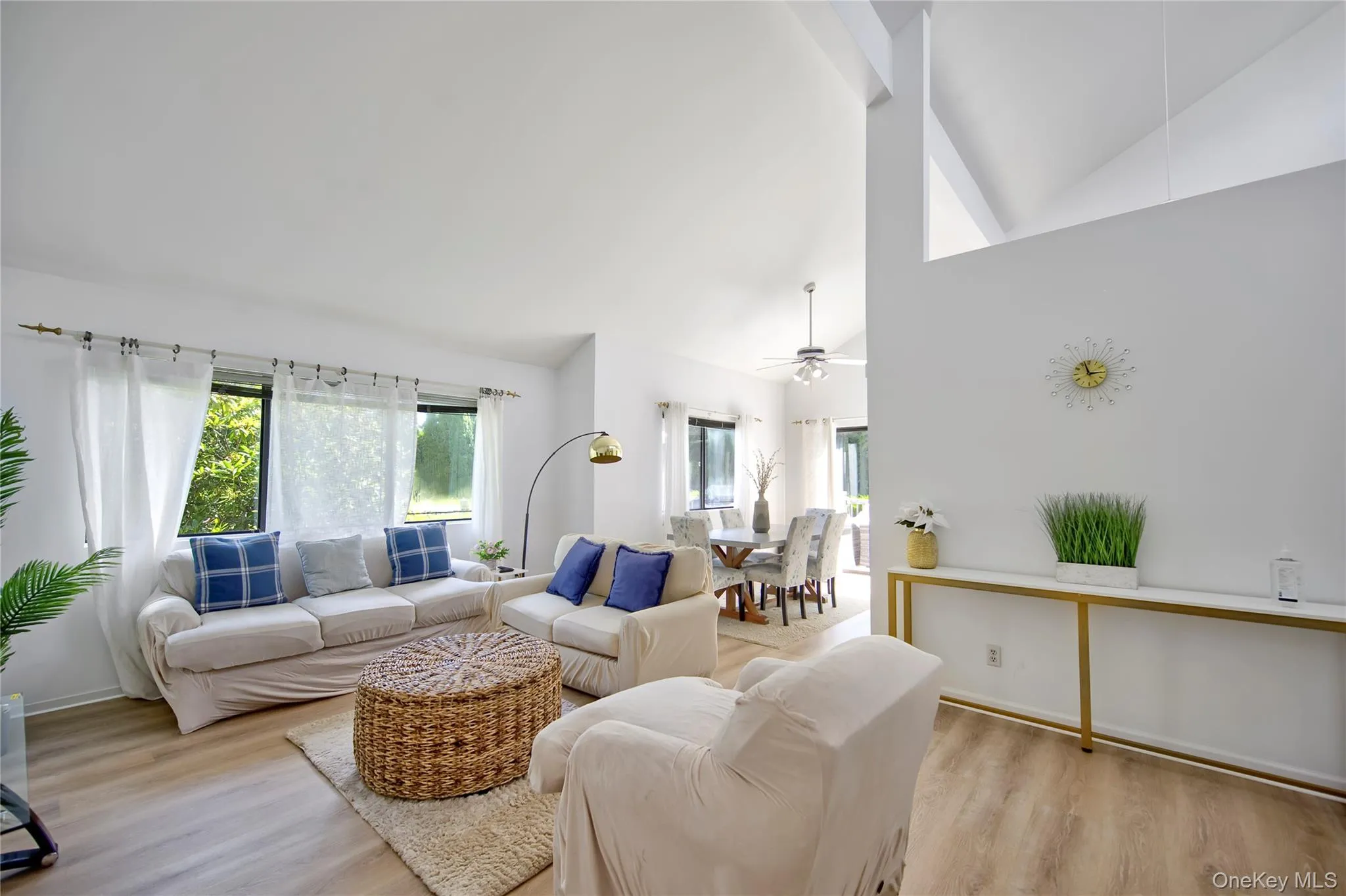 Living area featuring light wood-style flooring, high vaulted ceiling, and ceiling fan Living area featuring light wood-style flooring, high vaulted ceiling, and ceiling fan