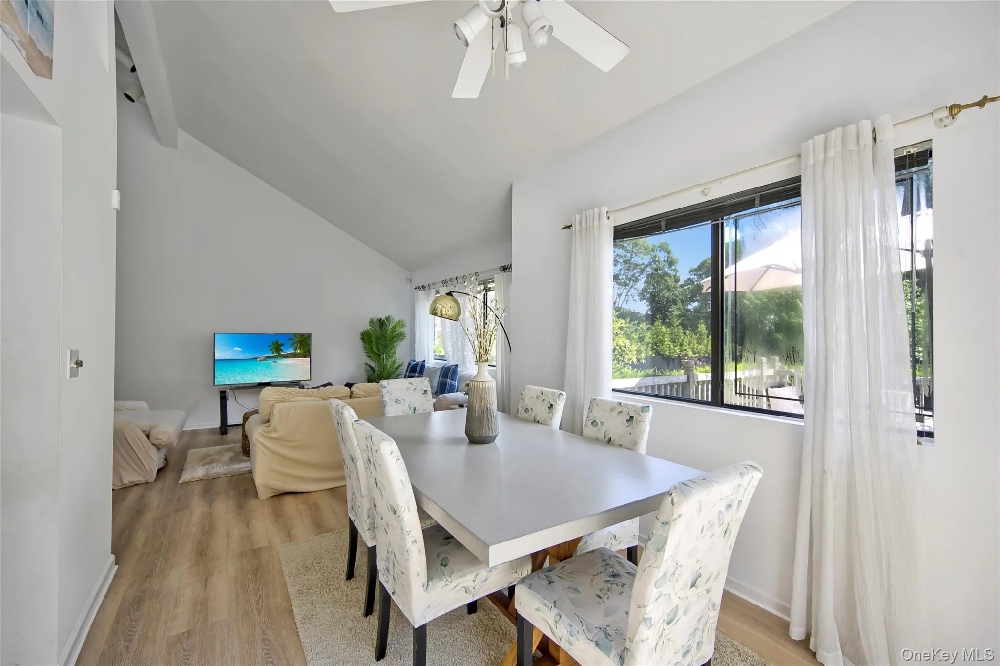 Dining area featuring lofted ceiling, light wood-style floors, and a ceiling fan Dining area featuring lofted ceiling, light wood-style floors, and a ceiling fan