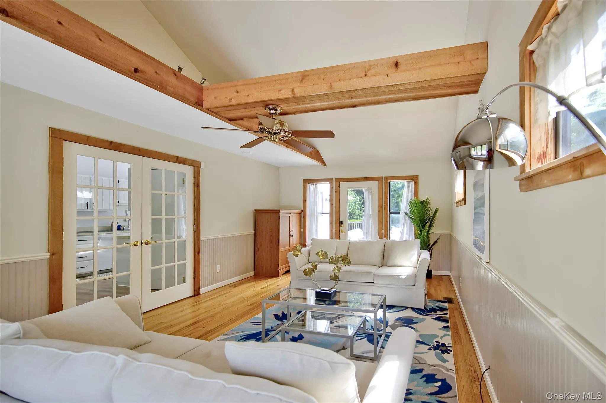 Living area featuring french doors, wainscoting, wood finished floors, and a ceiling fan Living area featuring french doors, wainscoting, wood finished floors, and a ceiling fan
