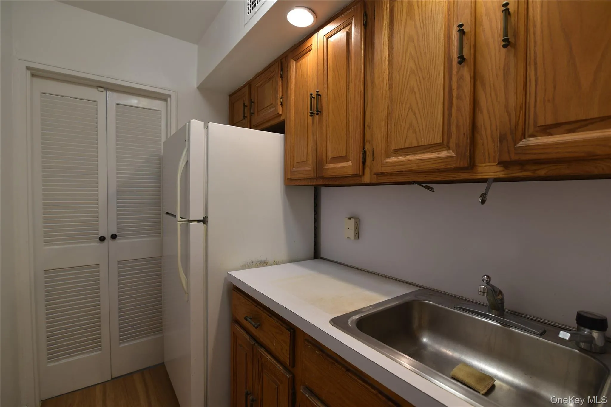 Kitchen featuring brown cabinetry, light countertops, and freestanding refrigerator Kitchen featuring brown cabinetry, light countertops, and freestanding refrigerator