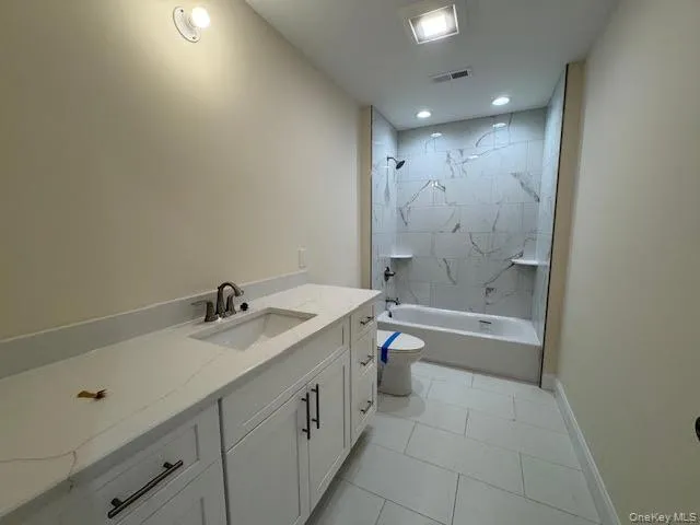 Bathroom featuring vanity, shower / bath combination, light tile patterned flooring, and recessed lighting Bathroom featuring vanity, shower / bath combination, light tile patterned flooring, and recessed lighting
