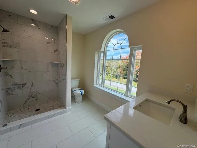 Full bath with vanity, a marble-look shower, light tile patterned floors, and recessed lighting Full bath with vanity, a marble-look shower, light tile patterned floors, and recessed lighting