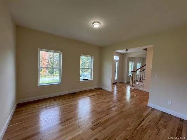 Empty room featuring light wood finished floors and stairway Empty room featuring light wood finished floors and stairway