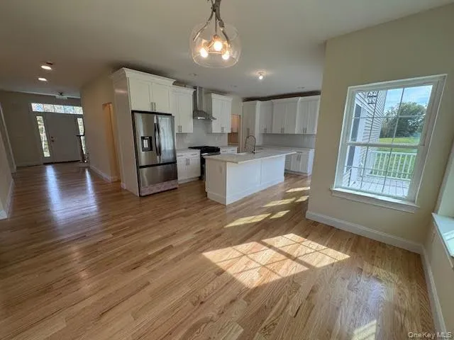 Kitchen featuring open floor plan, white cabinets, and stainless steel fridge Kitchen featuring open floor plan, white cabinets, and stainless steel fridge