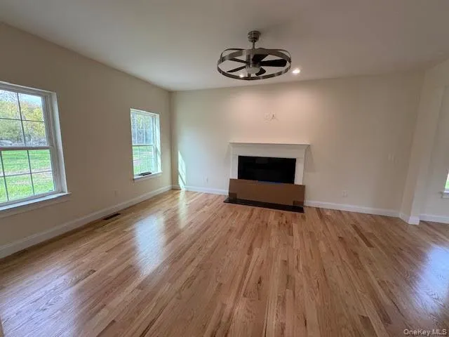 Unfurnished living room with natural sunlight, a fireplace, light wood finished floors, recessed lighting, and a ceiling fan Unfurnished living room with natural sunlight, a fireplace, light wood finished floors, recessed lighting, and a ceiling fan