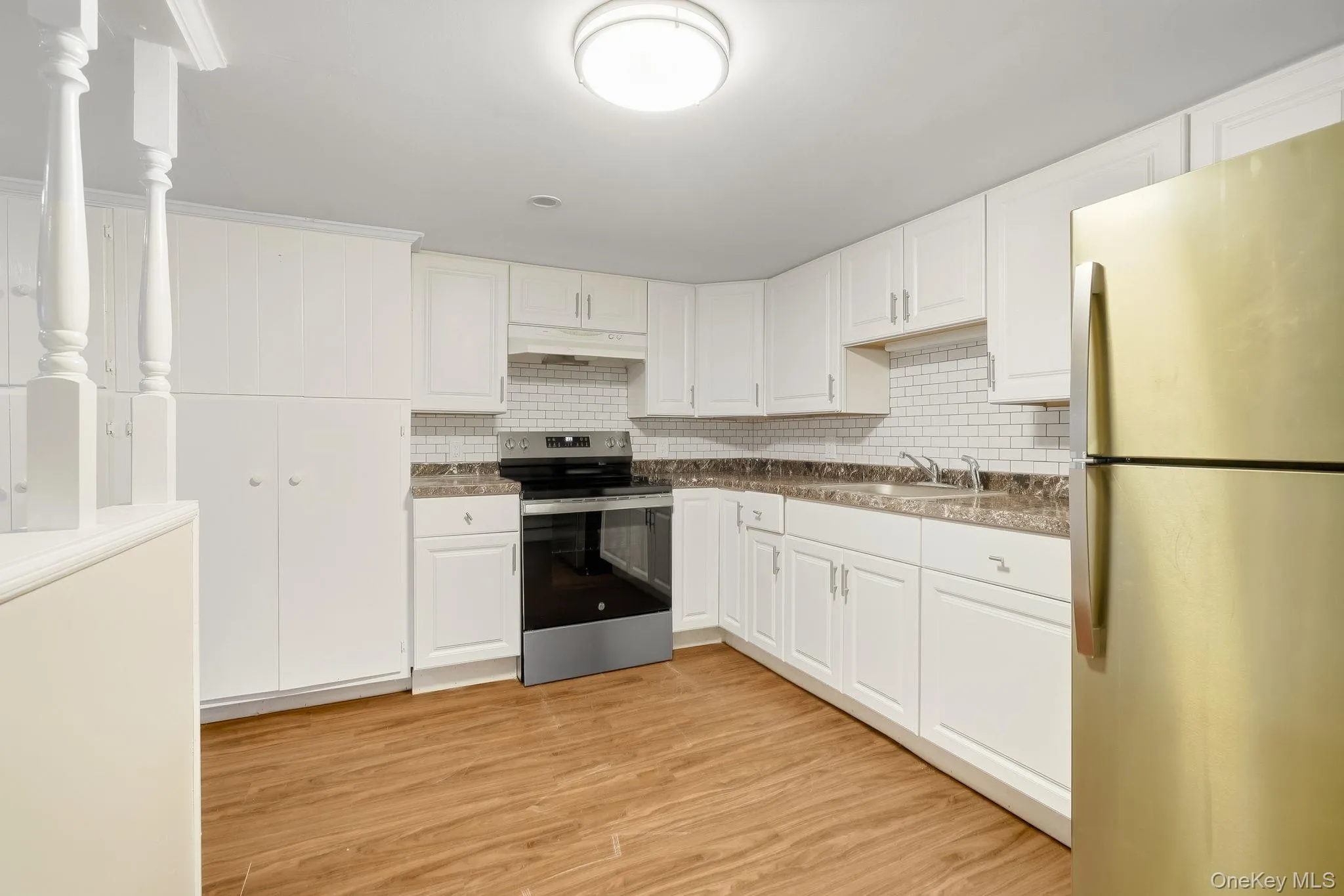 Kitchen with appliances with stainless steel finishes, backsplash, and white cabinetry Kitchen with appliances with stainless steel finishes, backsplash, and white cabinetry