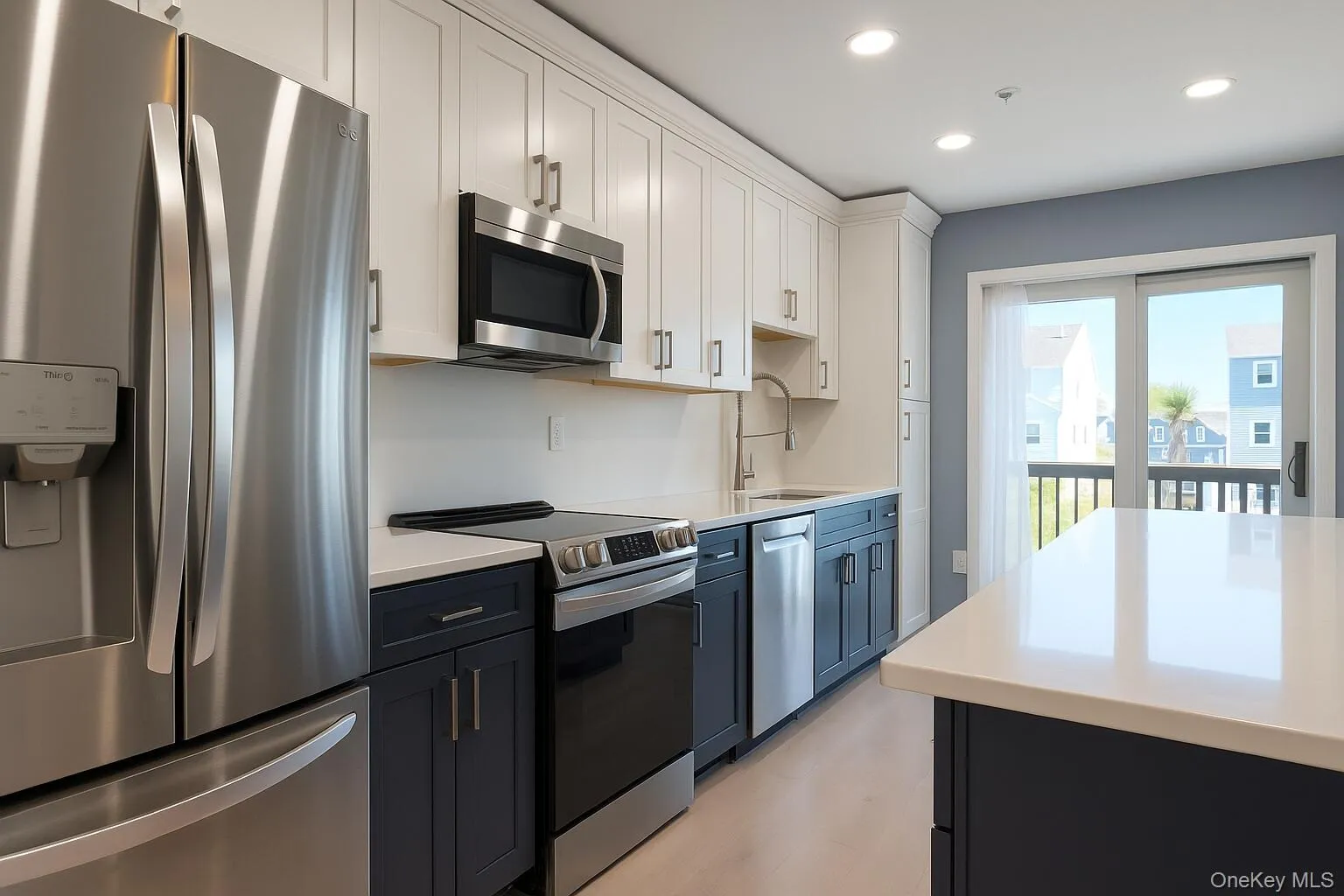 Kitchen featuring appliances with stainless steel finishes, white cabinets, recessed lighting, dark cabinets, and light stone counters Kitchen featuring appliances with stainless steel finishes, white cabinets, recessed lighting, dark cabinets, and light stone counters