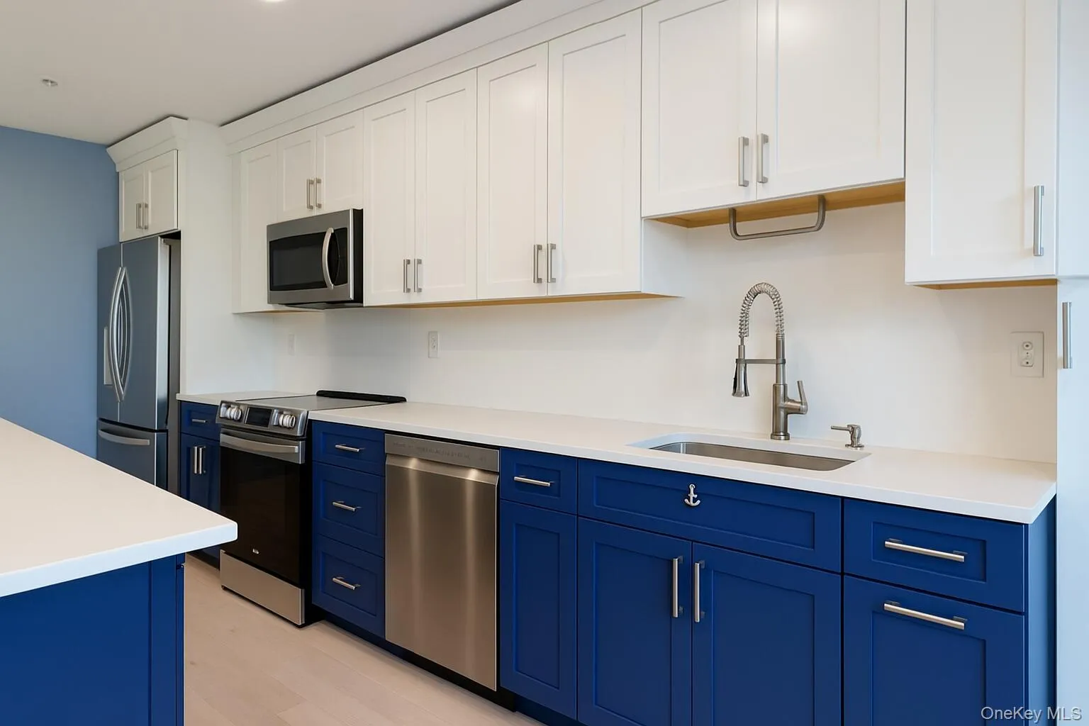 Kitchen featuring blue cabinetry, white cabinets, appliances with stainless steel finishes, and light wood-style flooring Kitchen featuring blue cabinetry, white cabinets, appliances with stainless steel finishes, and light wood-style flooring