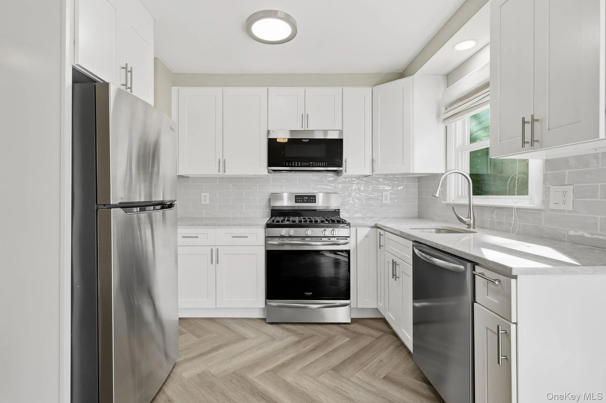 Kitchen with stainless steel appliances, light stone countertops, backsplash, white cabinetry, and recessed lighting Kitchen with stainless steel appliances, light stone countertops, backsplash, white cabinetry, and recessed lighting