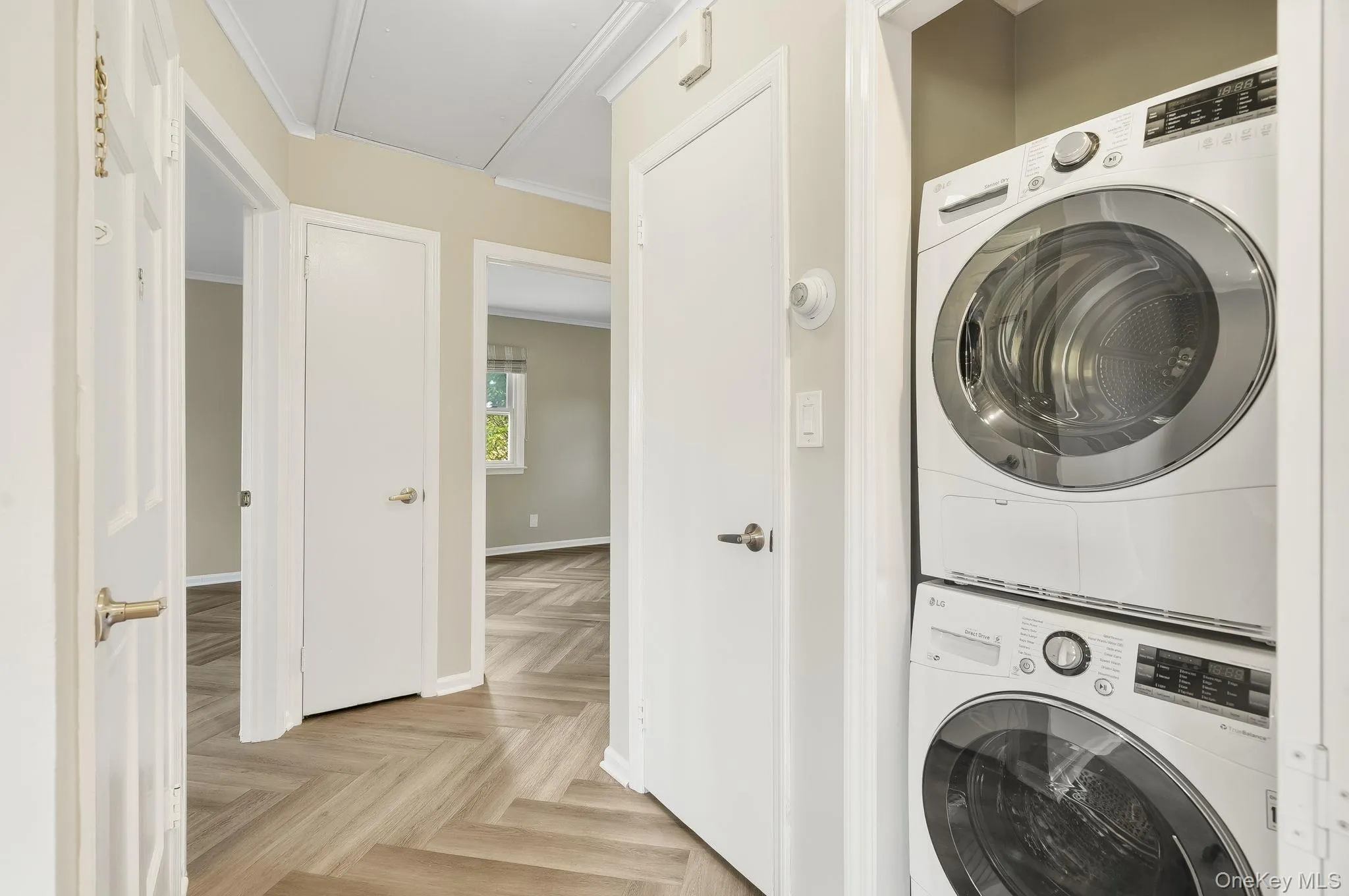 Laundry room featuring stacked washer and clothes dryer, attic access, and crown molding Laundry room featuring stacked washer and clothes dryer, attic access, and crown molding