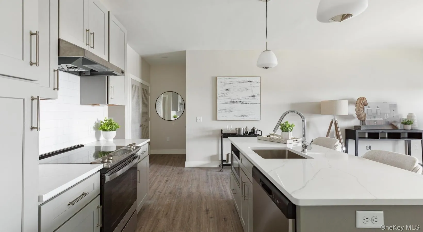 Kitchen featuring appliances with stainless steel finishes, under cabinet range hood, decorative light fixtures, dark wood-style floors, and a center island with sink Kitchen featuring appliances with stainless steel finishes, under cabinet range hood, decorative light fixtures, dark wood-style floors, and a center island with sink