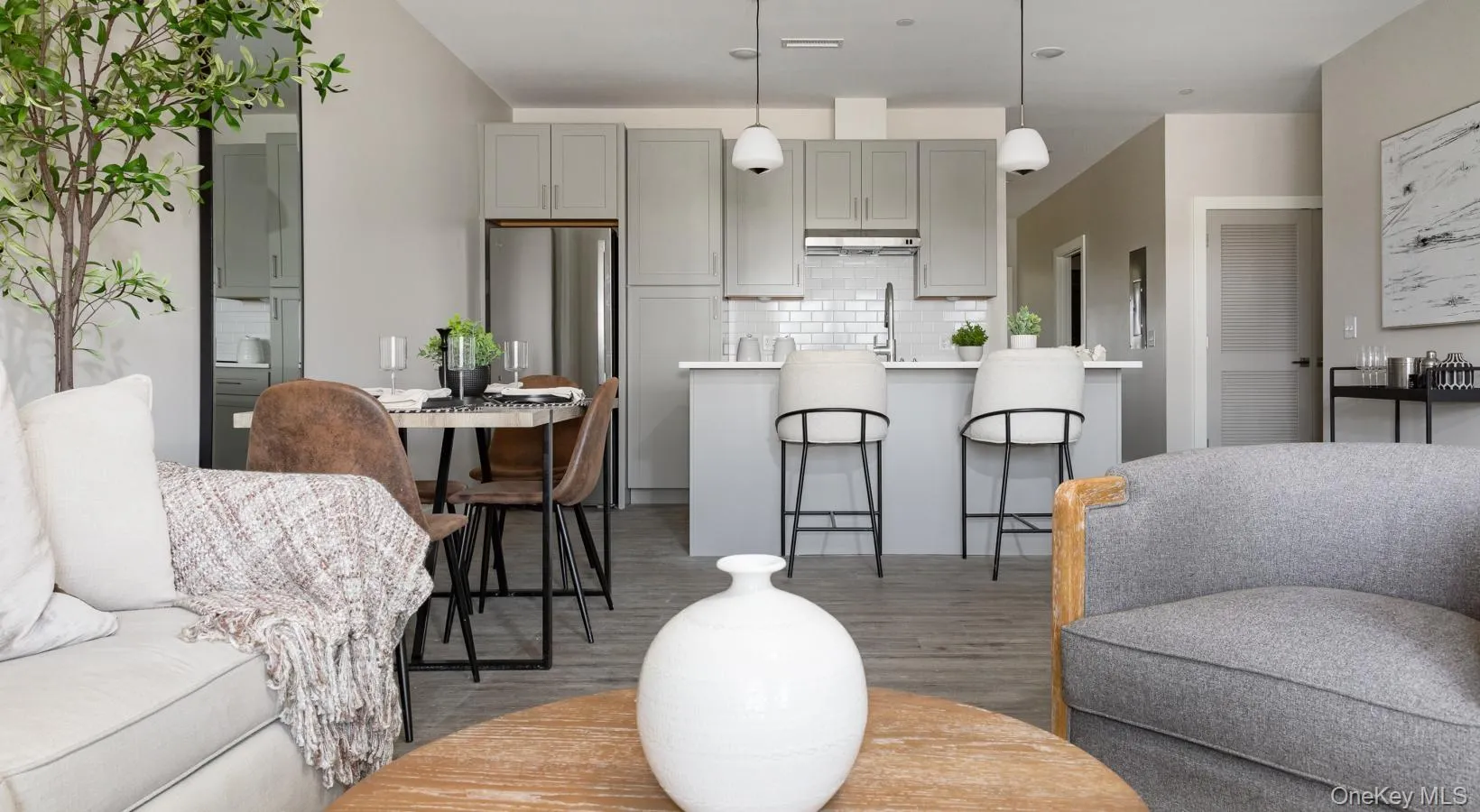 Kitchen with gray cabinetry, decorative backsplash, decorative light fixtures, freestanding refrigerator, and light wood-style floors Kitchen with gray cabinetry, decorative backsplash, decorative light fixtures, freestanding refrigerator, and light wood-style floors