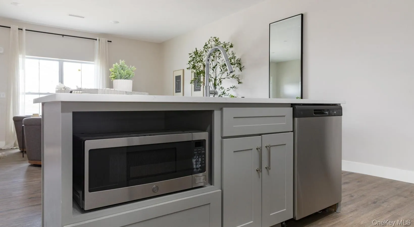 Kitchen with light wood finished floors, stainless steel appliances, and gray cabinetry Kitchen with light wood finished floors, stainless steel appliances, and gray cabinetry