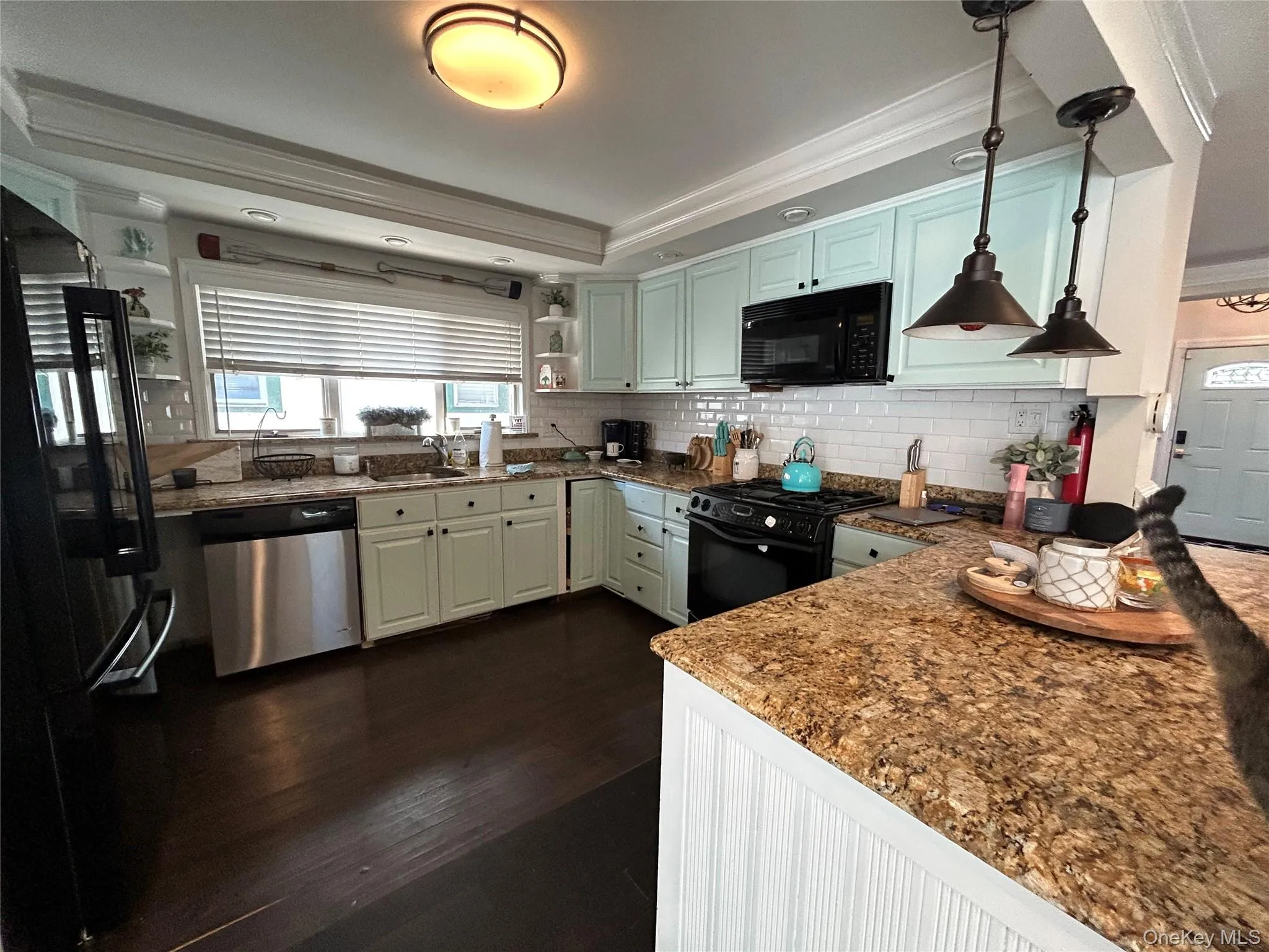 Kitchen featuring open shelves, black appliances, dark wood finished floors, dark stone countertops, and crown molding Kitchen featuring open shelves, black appliances, dark wood finished floors, dark stone countertops, and crown molding