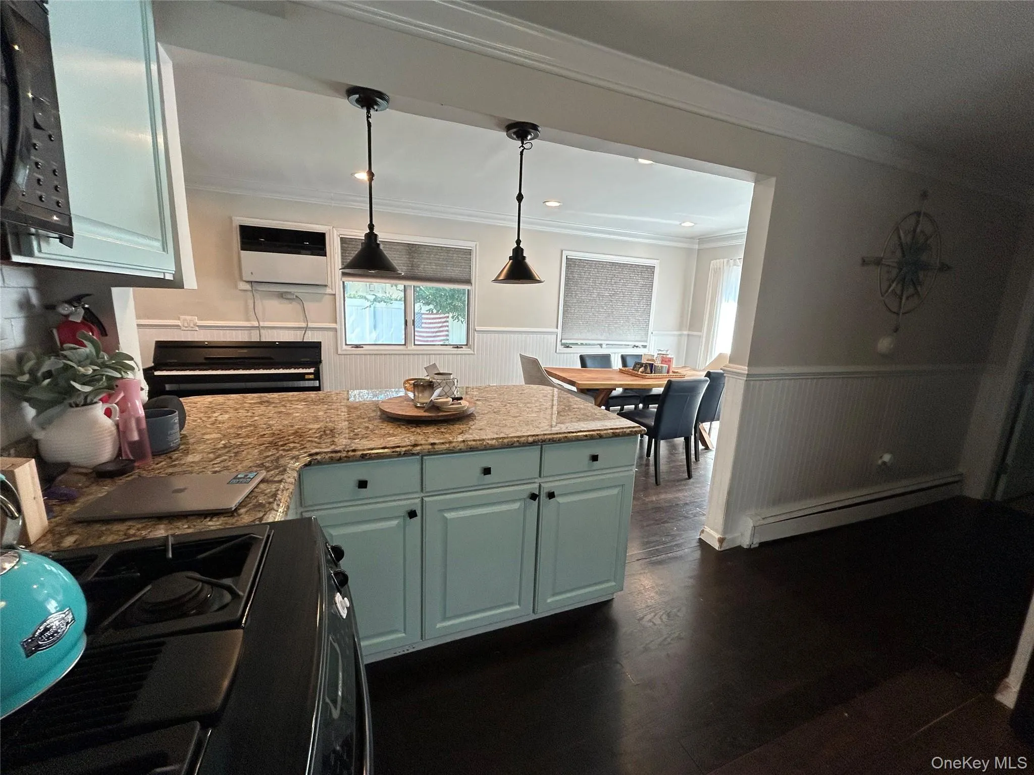 Kitchen featuring dark wood finished floors, light stone counters, a peninsula, range, and a baseboard heating unit Kitchen featuring dark wood finished floors, light stone counters, a peninsula, range, and a baseboard heating unit