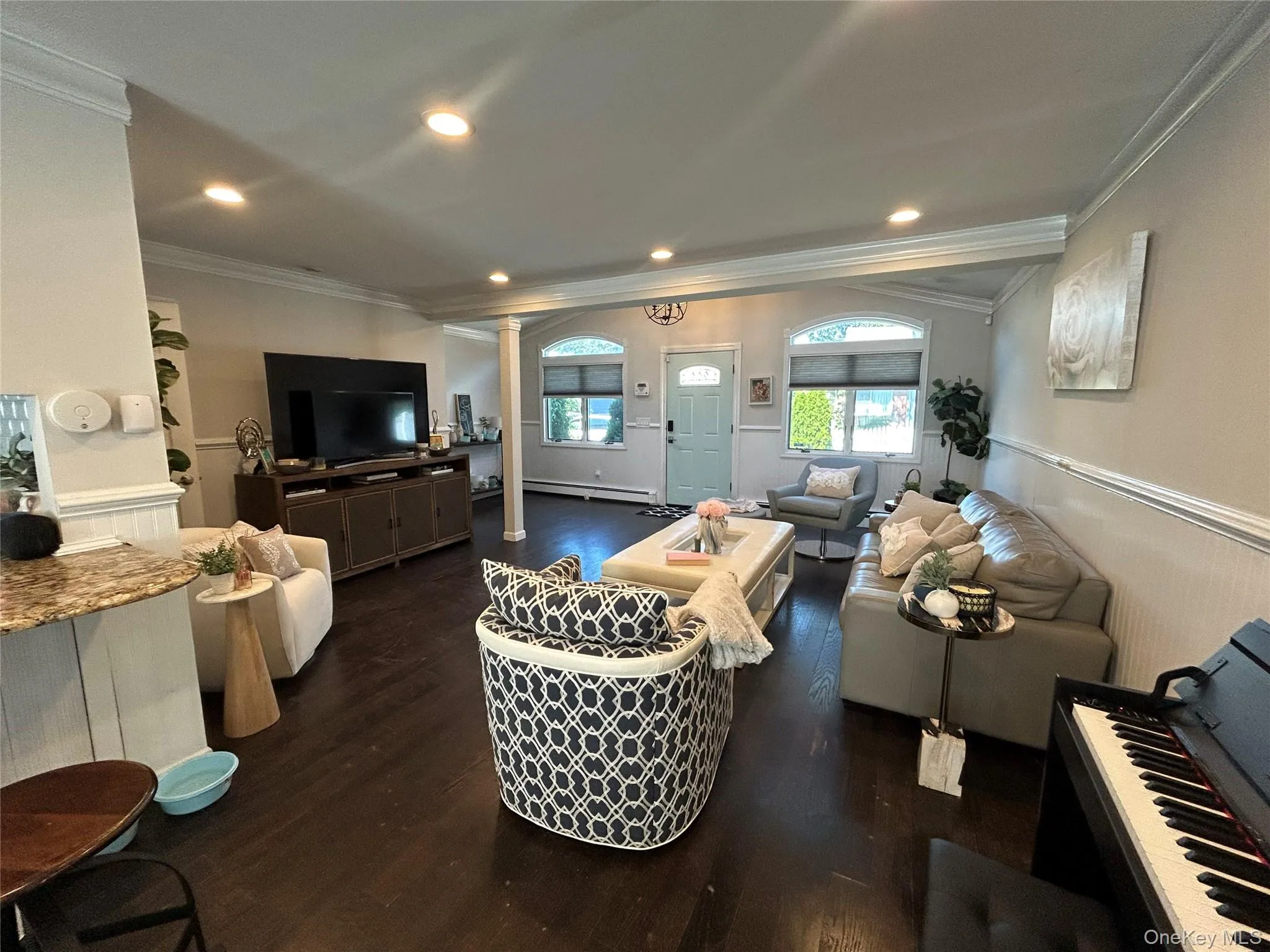 Living room with ornamental molding, ornate columns, dark wood finished floors, recessed lighting, and baseboard heating Living room with ornamental molding, ornate columns, dark wood finished floors, recessed lighting, and baseboard heating