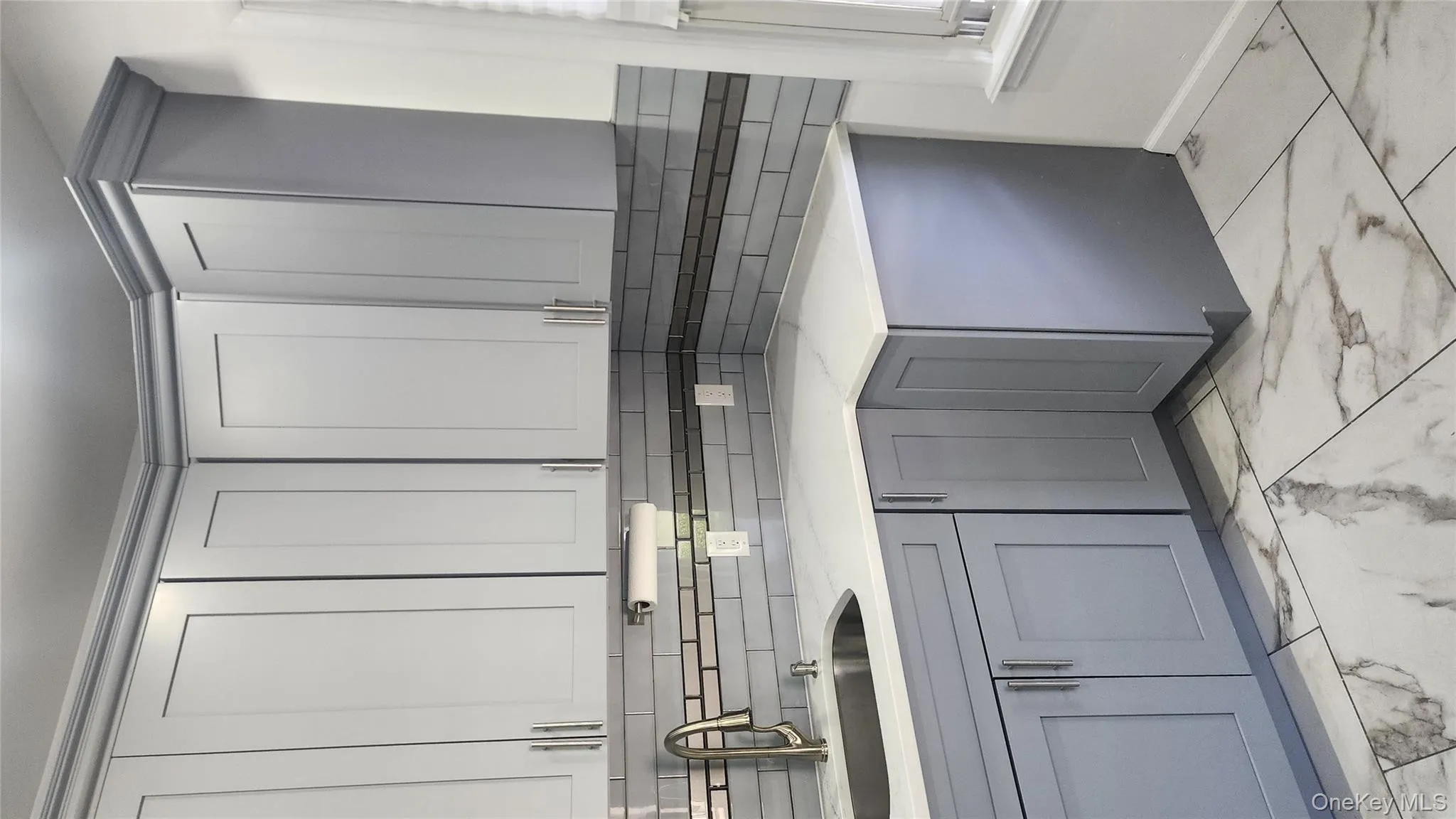 Kitchen featuring gray cabinets, light marble finish flooring, tasteful backsplash, light stone countertops, and white cabinets Kitchen featuring gray cabinets, light marble finish flooring, tasteful backsplash, light stone countertops, and white cabinets