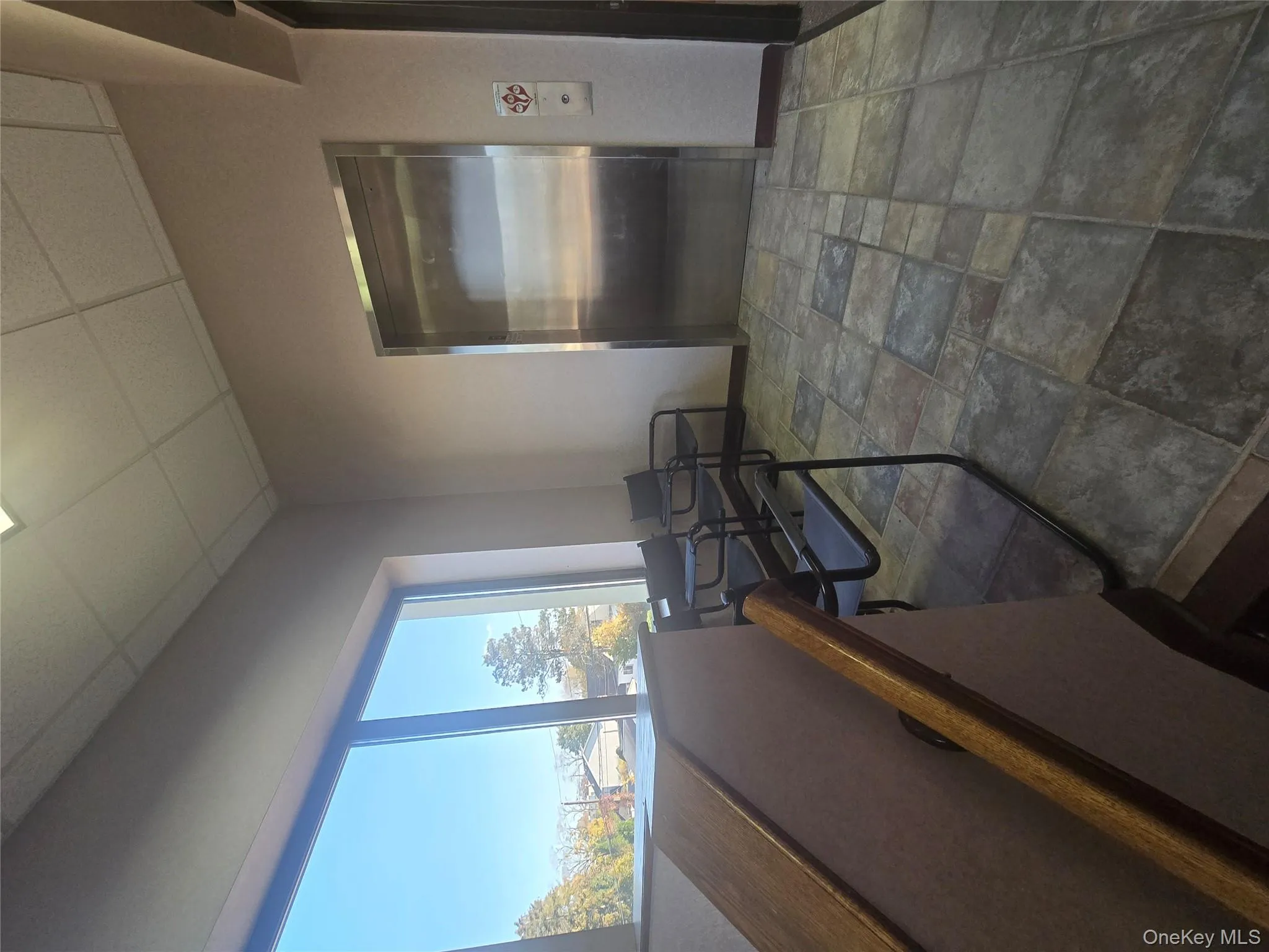 Corridor featuring a paneled ceiling, stone finish flooring, and elevator Corridor featuring a paneled ceiling, stone finish flooring, and elevator