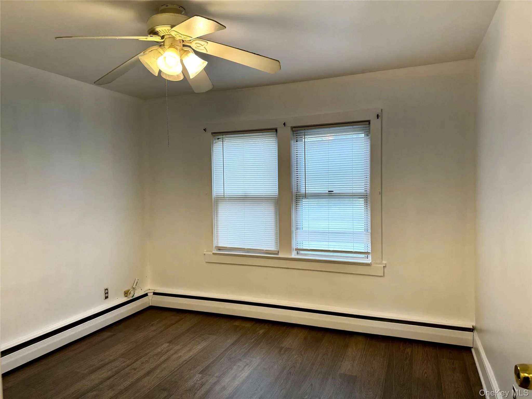 Bedroom with dark wood-style flooring, a ceiling fan, and baseboard heating Bedroom with dark wood-style flooring, a ceiling fan, and baseboard heating