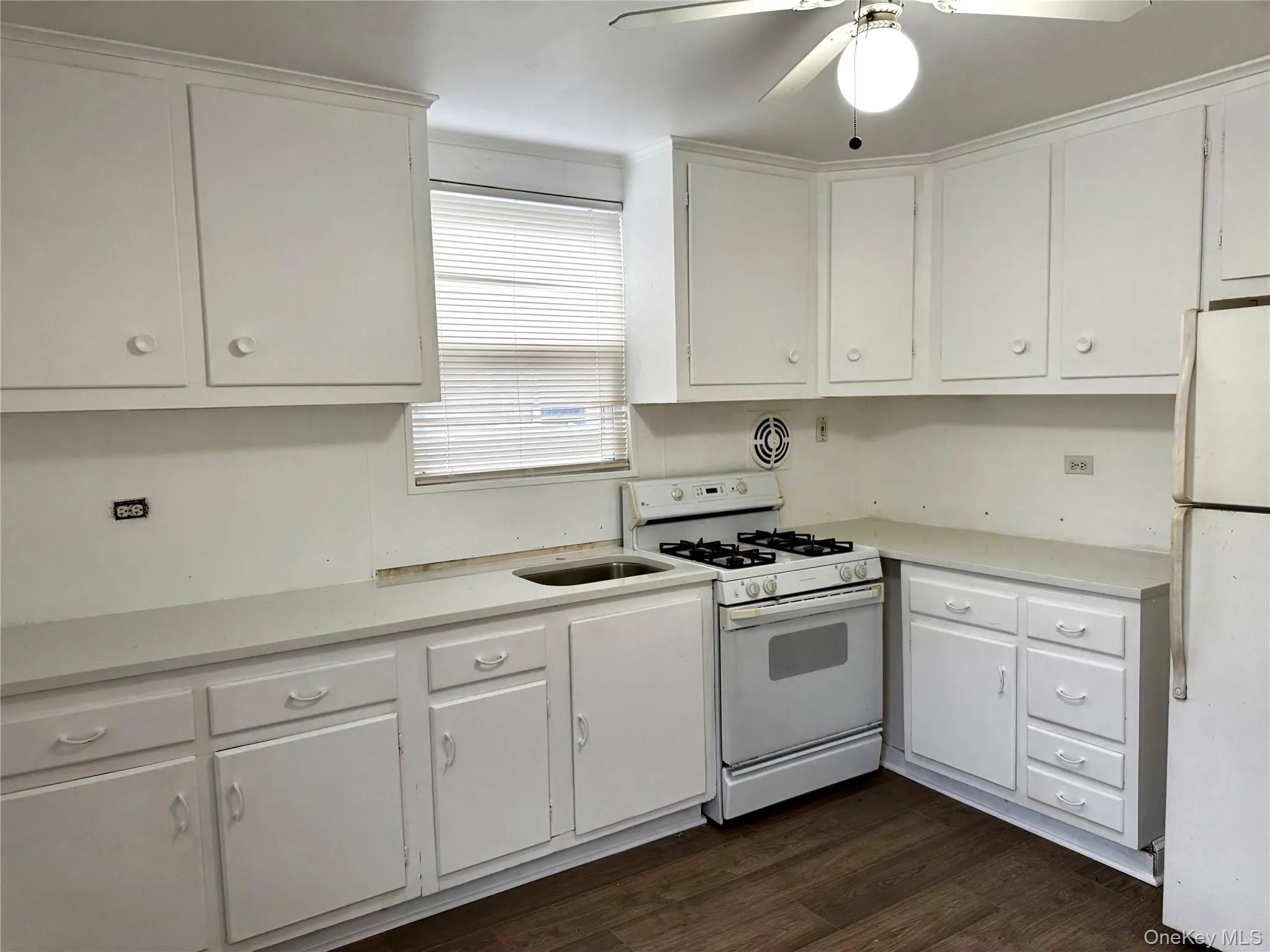 Kitchen featuring white appliances, white cabinets, dark wood-type flooring, and a ceiling fan Kitchen featuring white appliances, white cabinets, dark wood-type flooring, and a ceiling fan