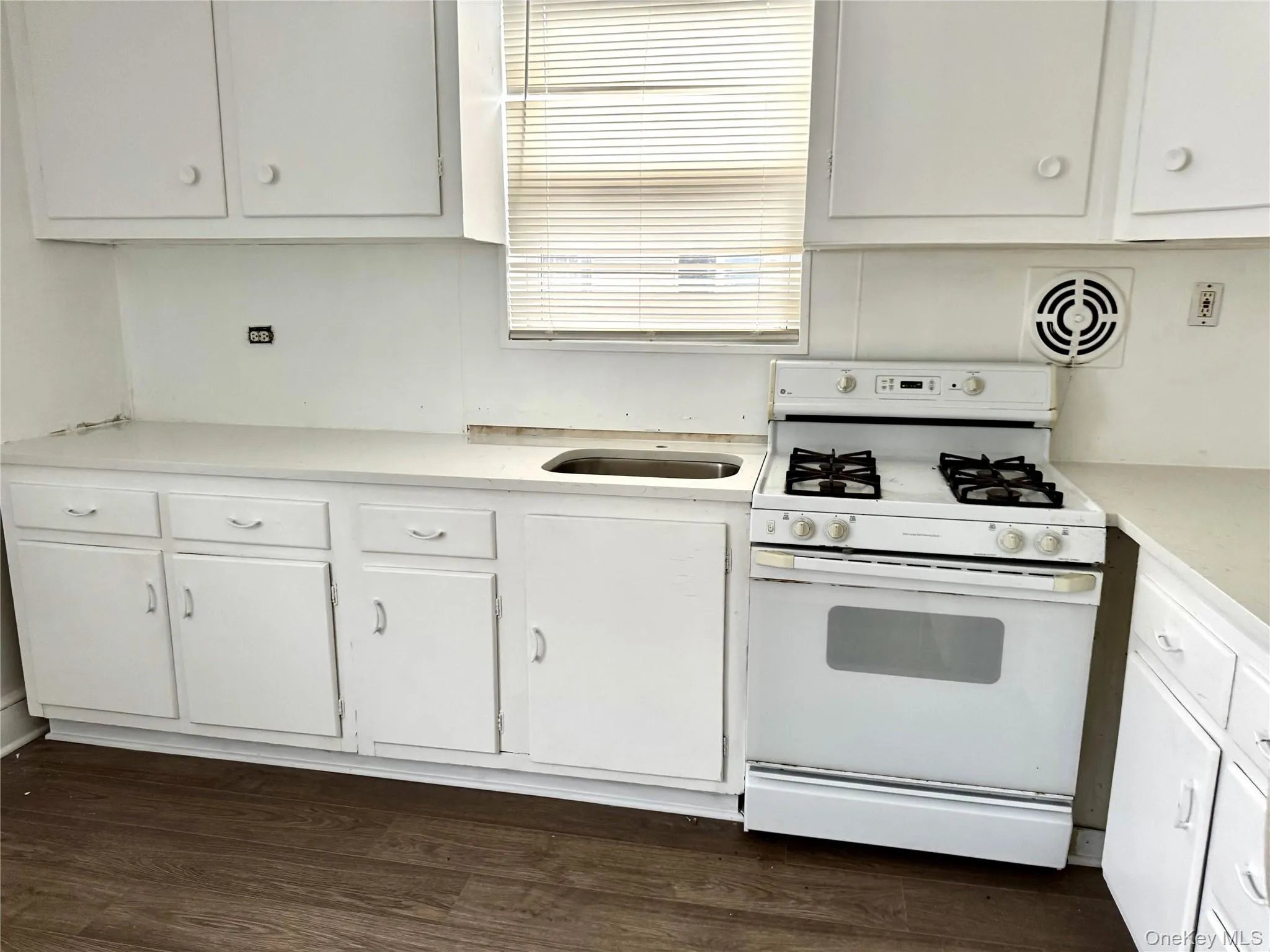 Kitchen featuring white gas stove, white cabinets, light countertops, and dark wood finished floors Kitchen featuring white gas stove, white cabinets, light countertops, and dark wood finished floors