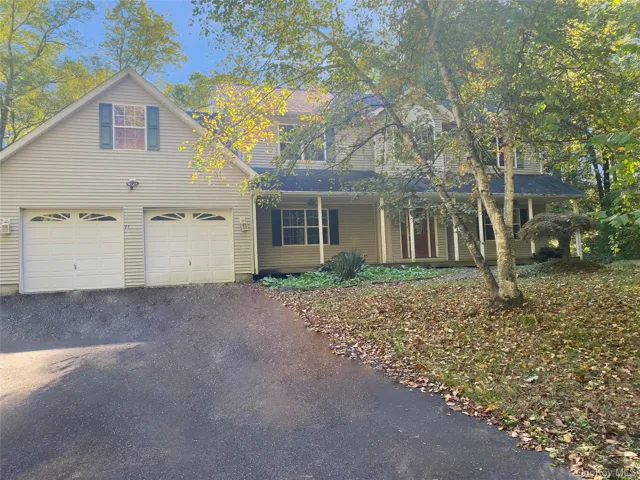 Traditional-style home with driveway, an attached garage, and a porch