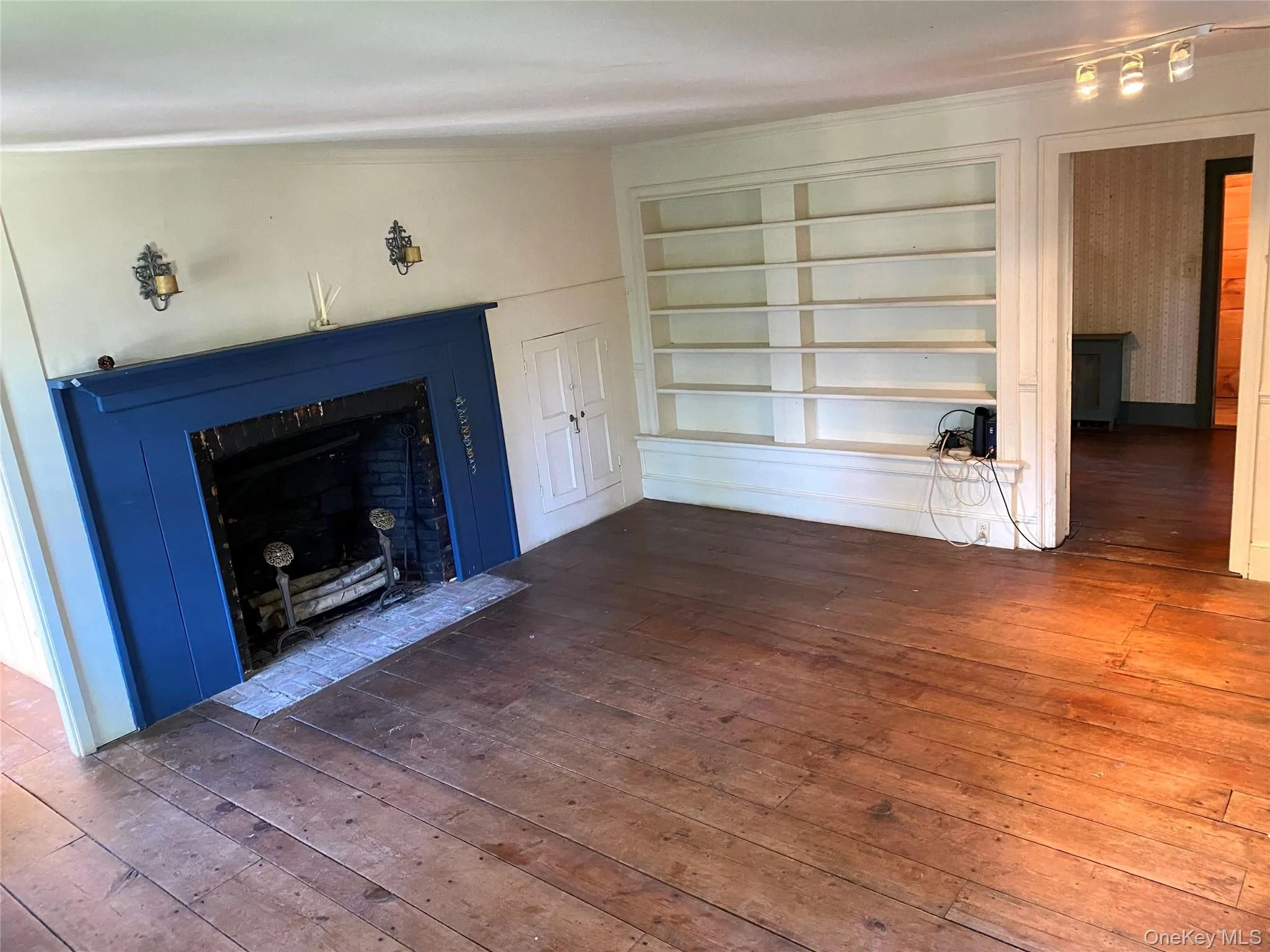 Unfurnished living room with a fireplace with flush hearth, built in features, and wood-type flooring Unfurnished living room with a fireplace with flush hearth, built in features, and wood-type flooring